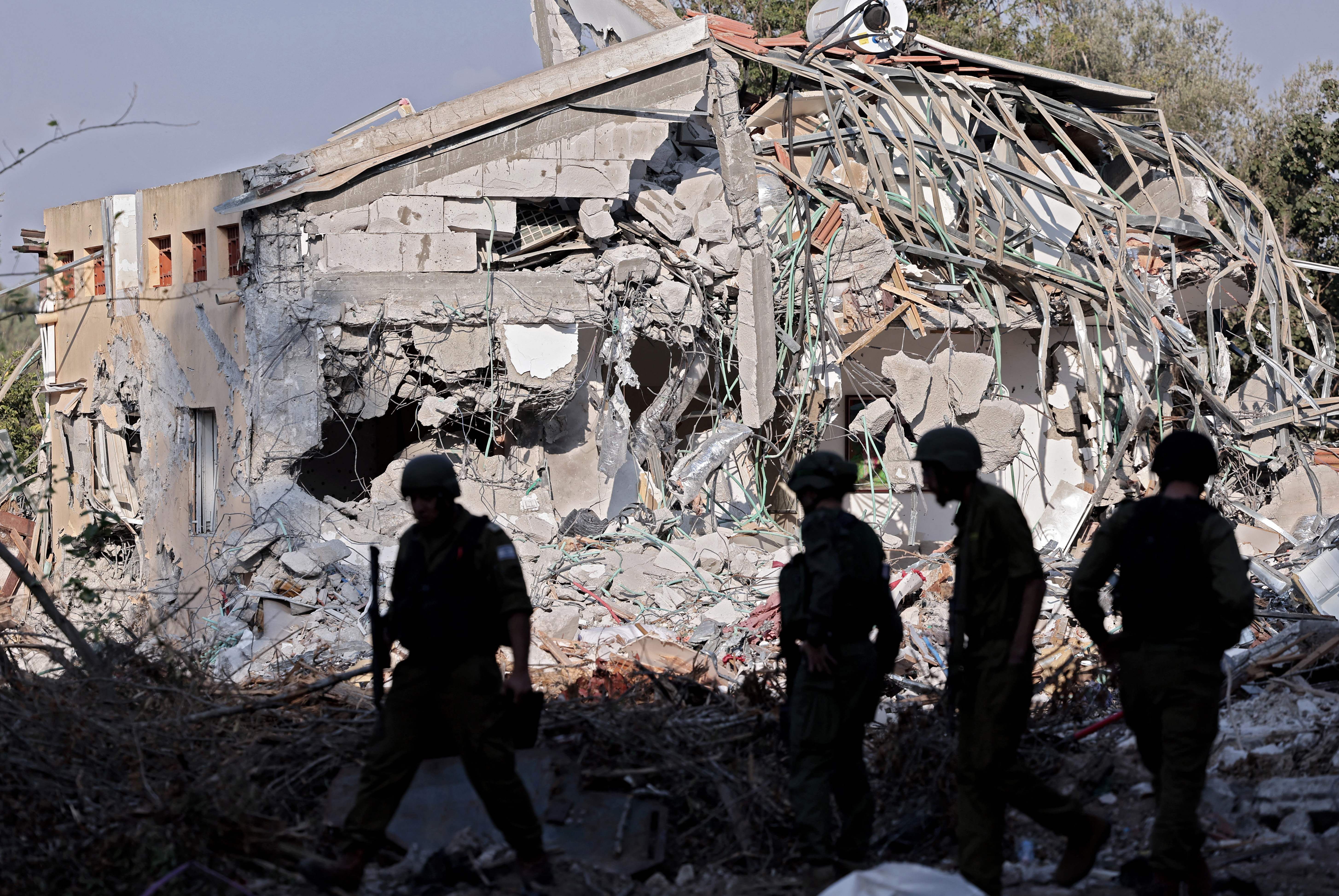 Israeli soldiers walk past a house destroyed in the October 7 attack by Hamas militants in Kibbutz Be'eri near the border with Gaza.