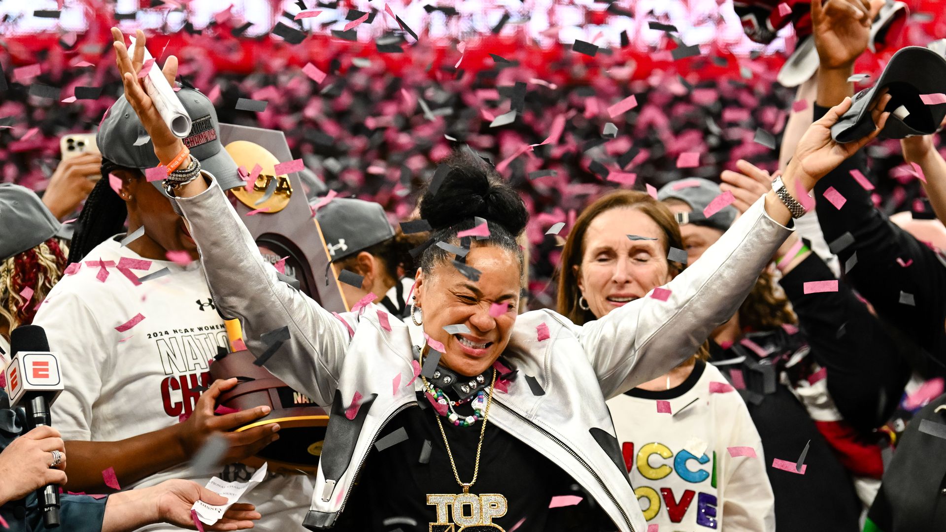 South Carolina head coach Dawn Staley smiling with her arms outstretched while being showered with confetti. 