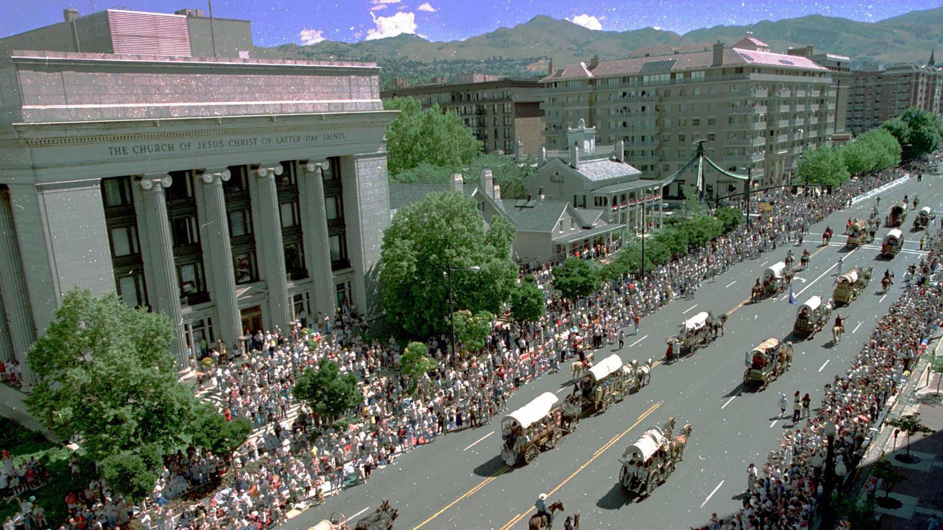 A parade of covered wagons on a Salt Lake City street