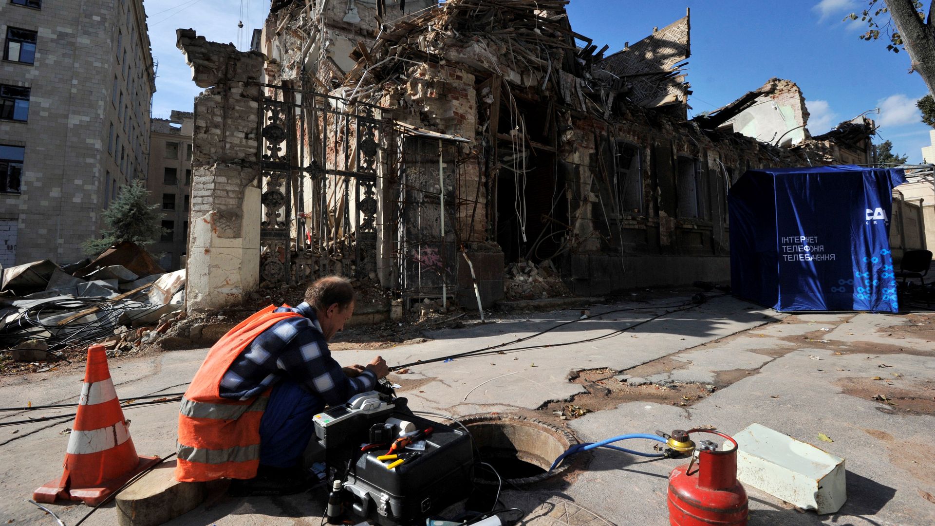 A worker repairing damaged technical installations outside of a destroyed building following shelling in the center of Kharkiv on Sept. 18.