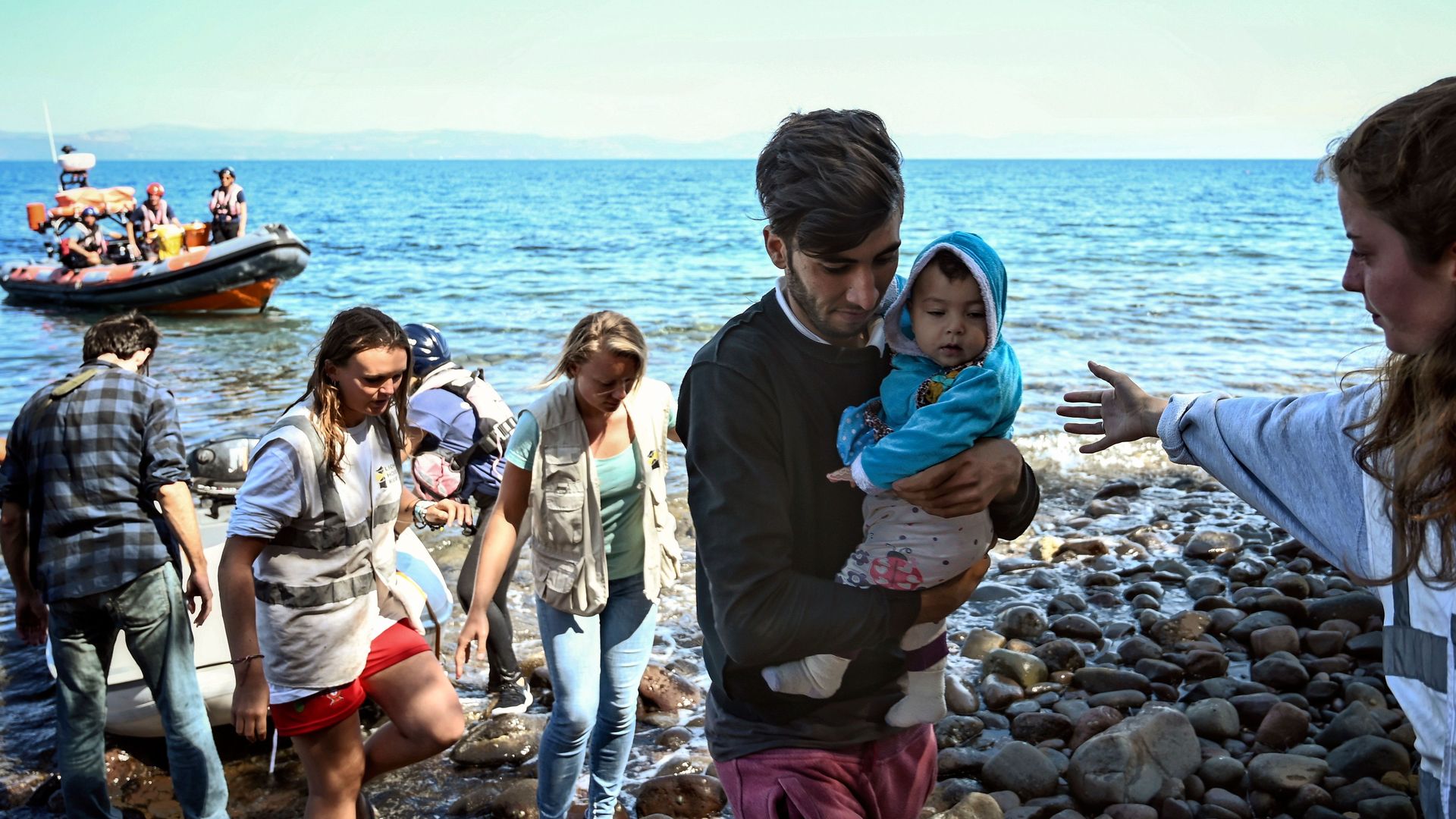 Migrants with a child, helped by rescuers arrive on the Greek island of Lesbos after crossing the Aegean Sea from Turkey