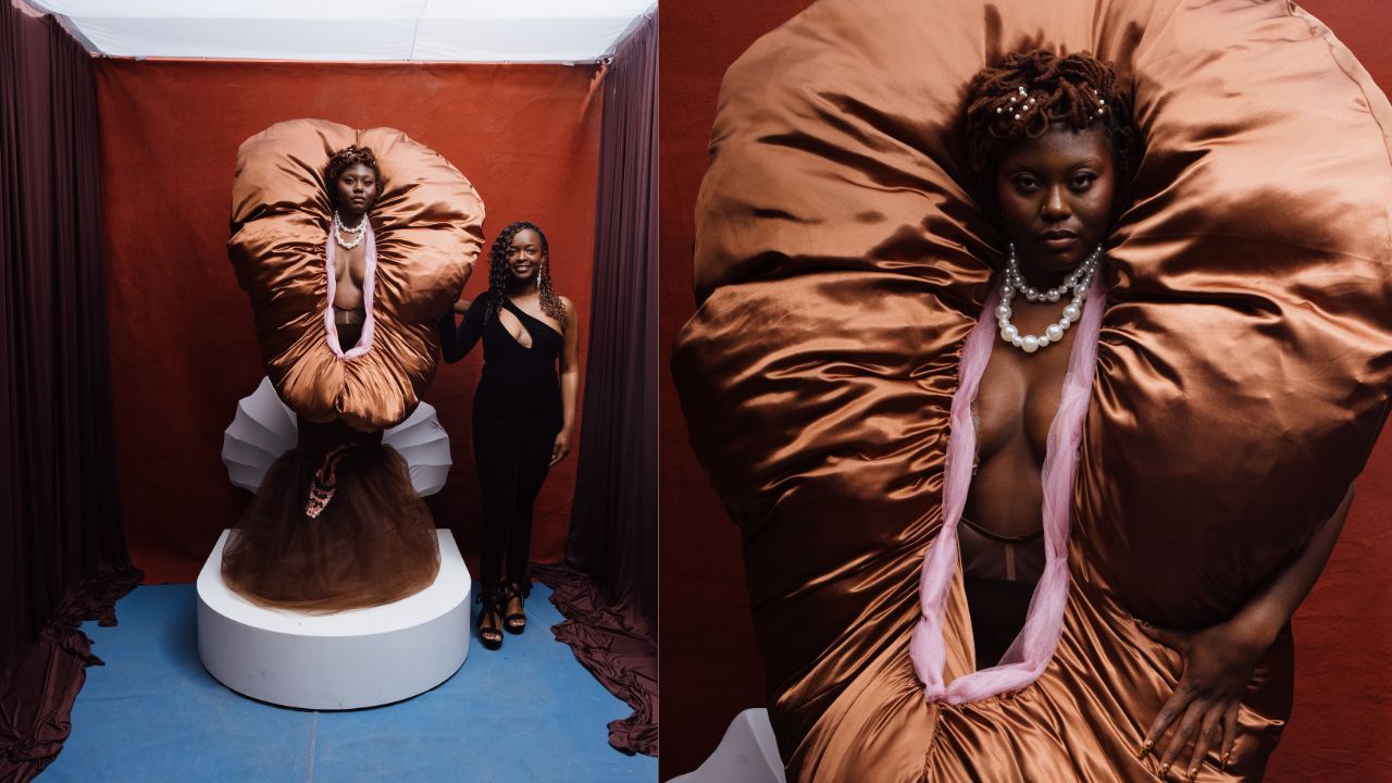 Two women pose in a red studio with a giant brown inflatable gown; one emerges from the dress on a pedestal, the other in black stands beside. A close-up shows a pearl necklace and pink scarf.