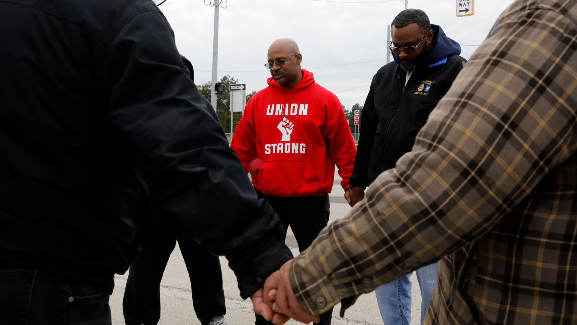 In this image, a man stands in a circle with "union strong" on his sweatshirt.