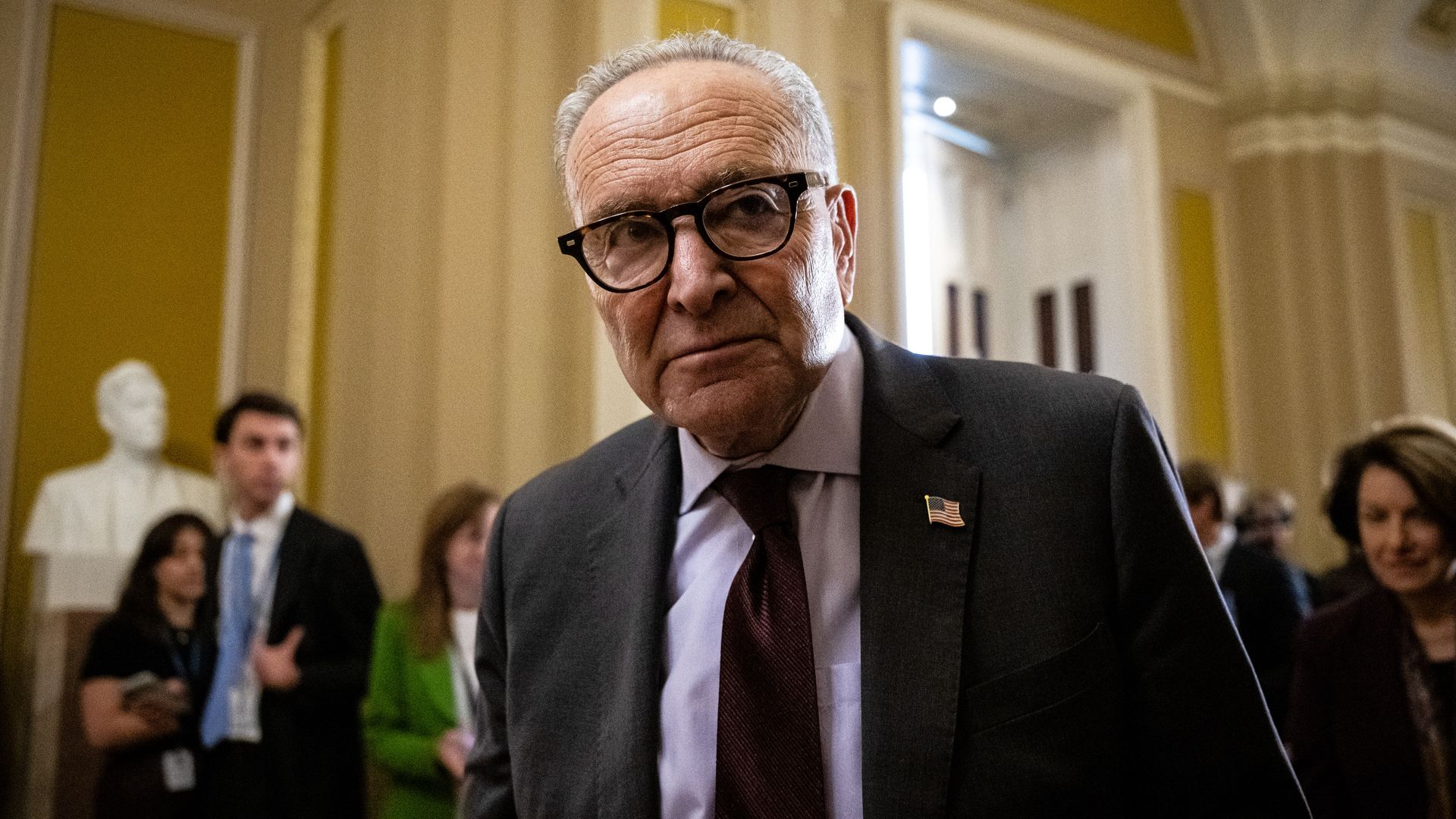 U.S. Senator Chuck Schumer standing at a podium in the Capitol building, speaking into a microphone at a news conference.