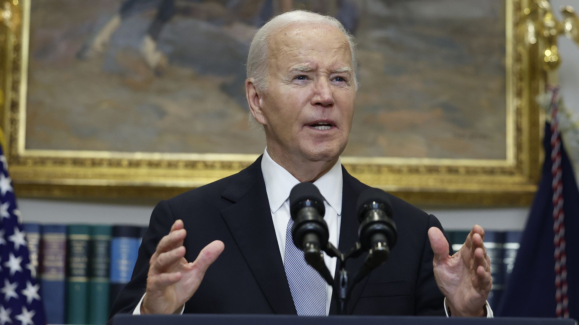 President Biden, wearing a gray suit and speaking at podium in the Roosevelt room.