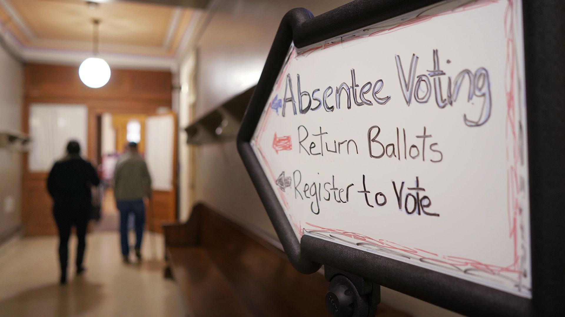Voters wait in line and cast their absentee ballots