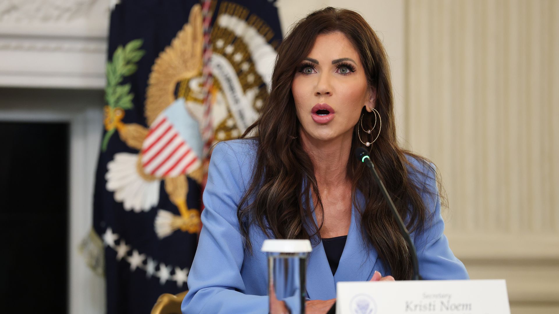 U.S. Secretary of Homeland Security Kristi Noem speaks during a roundtable discussion earlier this month. Her mouth is slightly open as she speaks, and she is wearing a blue suit.