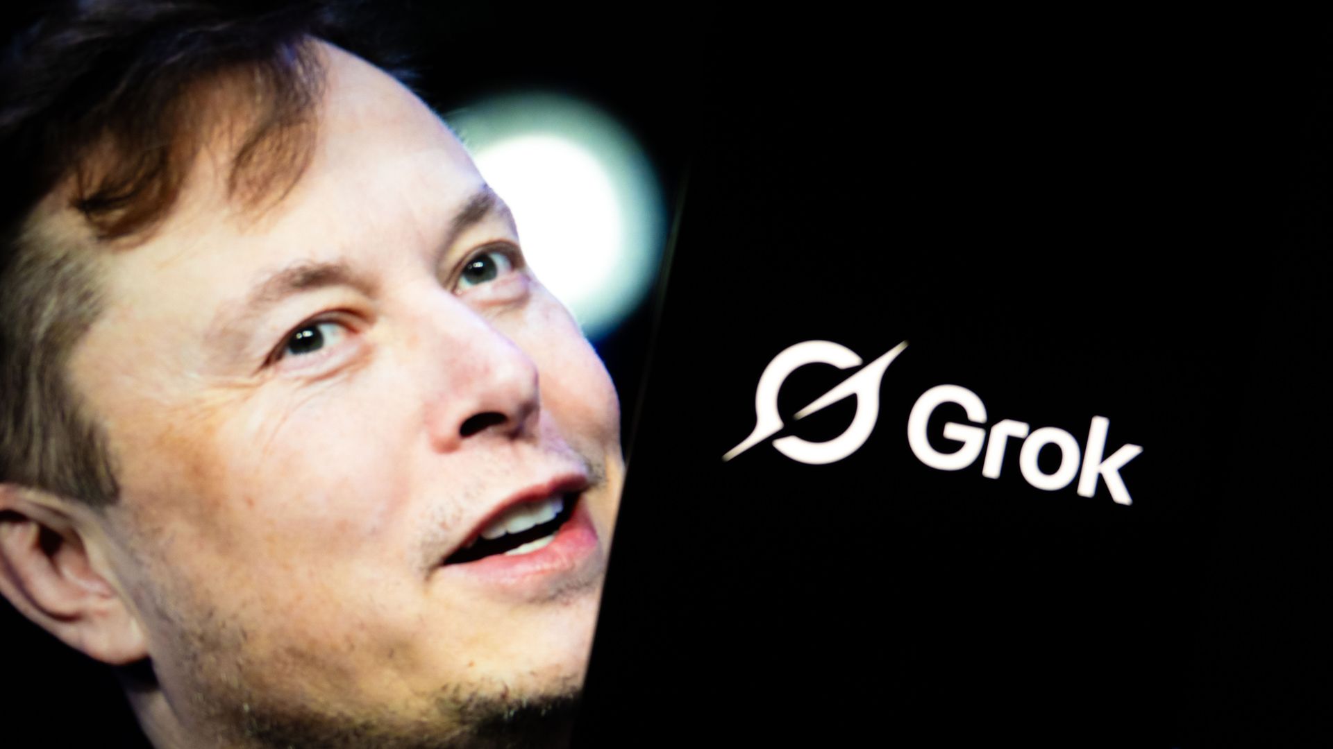 In this photo illustration, 'Grok' logo is seen displayed on a mobile phone screen in front of a picture of Elon Musk in Ankara, Turkiye on July 17, 2025. Photo: Didem Mente/Anadolu via Getty Images