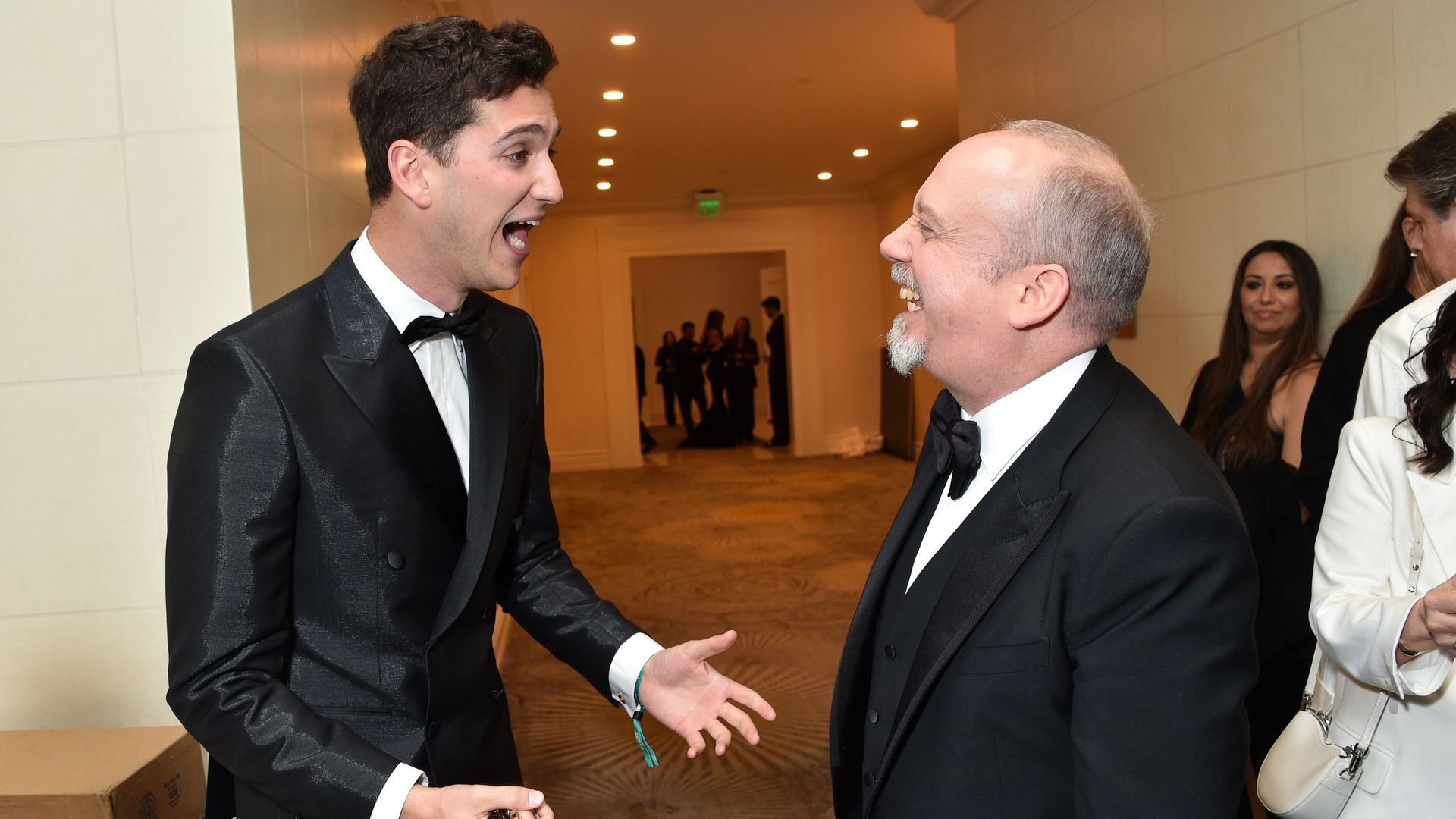 Photo of two people laughing while standing, having a conversation 