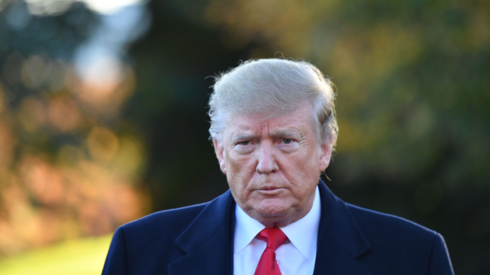 Donald Trump looks steadfastly ahead in a coat, shirt and tie while on the White House lawn