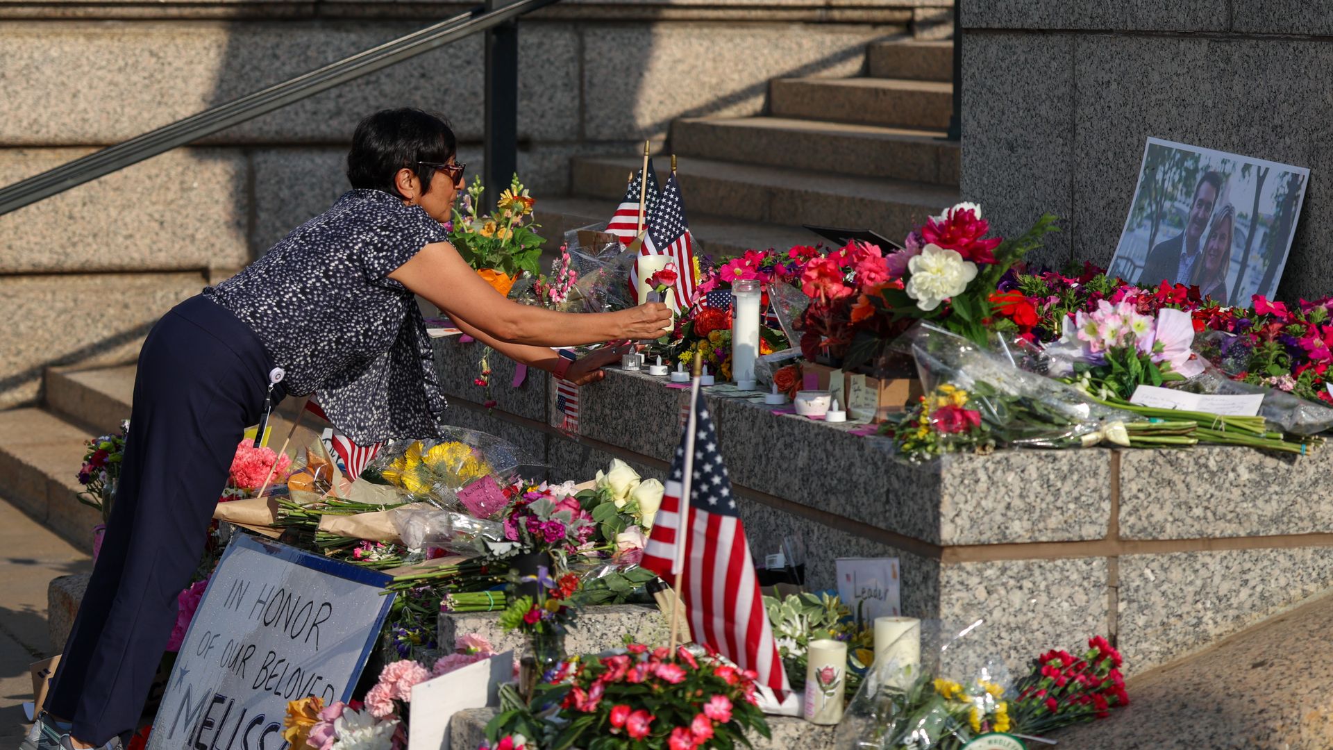 A woman lays a flower at the site of a memorial for a Minnesota state lawmaker and her husband.