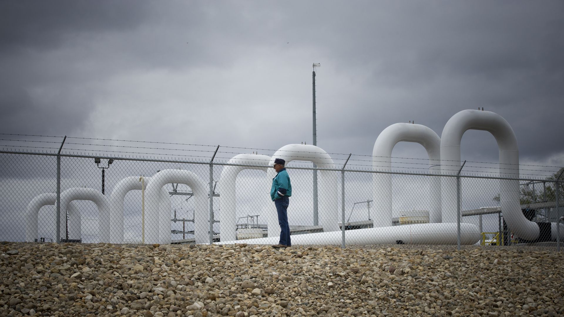 man stands in front of white pipes at oil pumping station