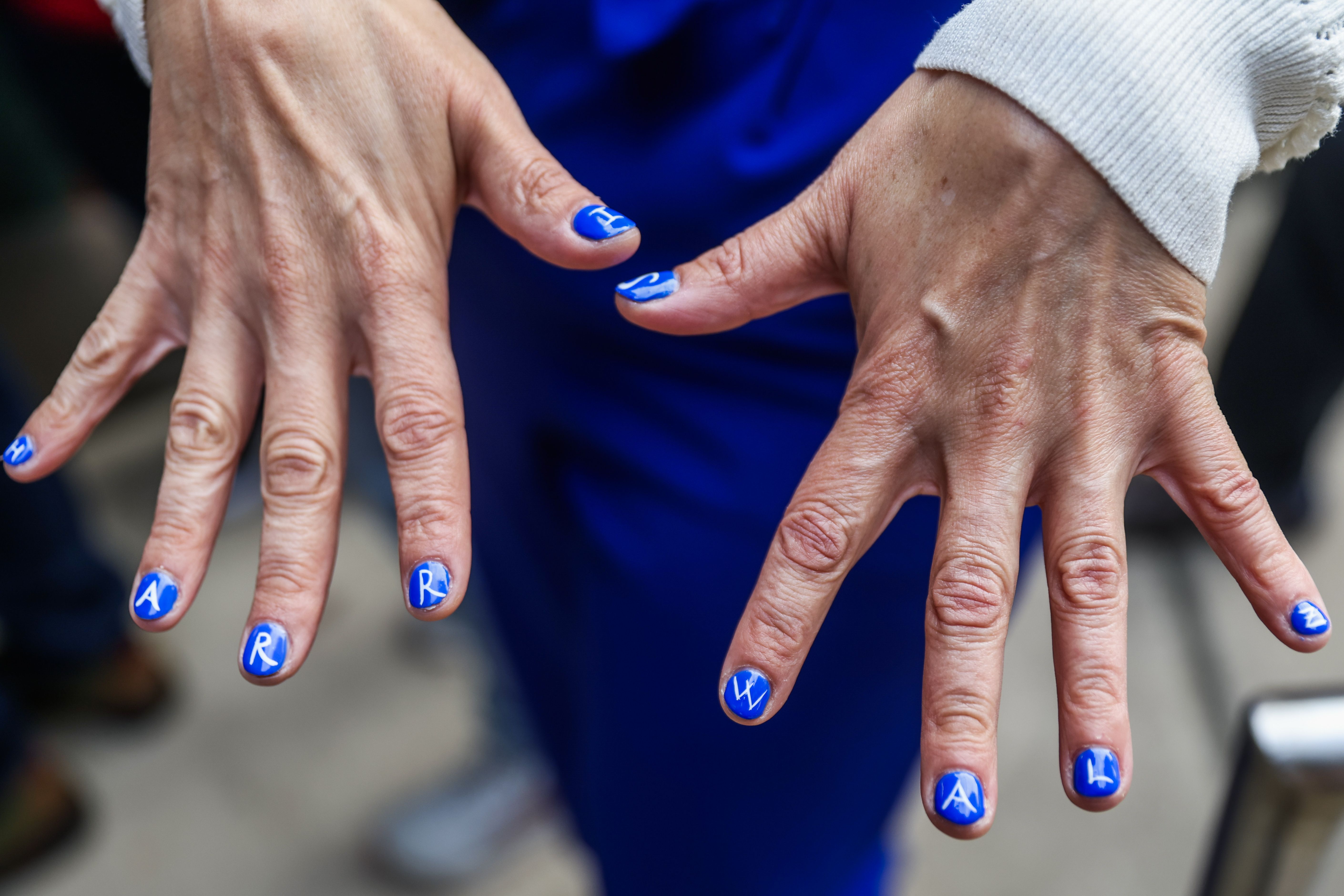 A woman shows her nails which are painted to spell out HARRISWALZ. 