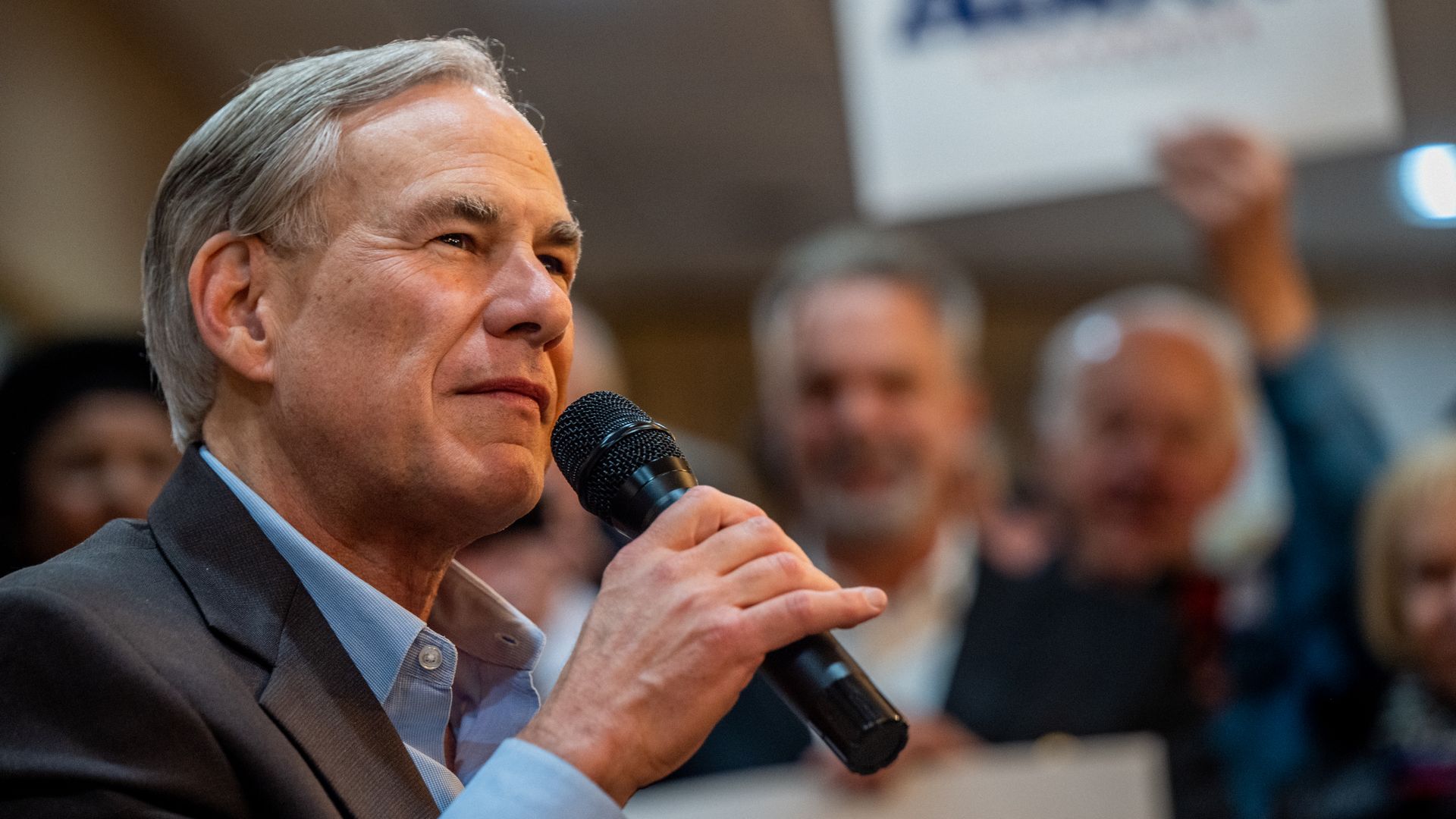 Photo of Greg Abbott speaking into a mic as supporters stand around him