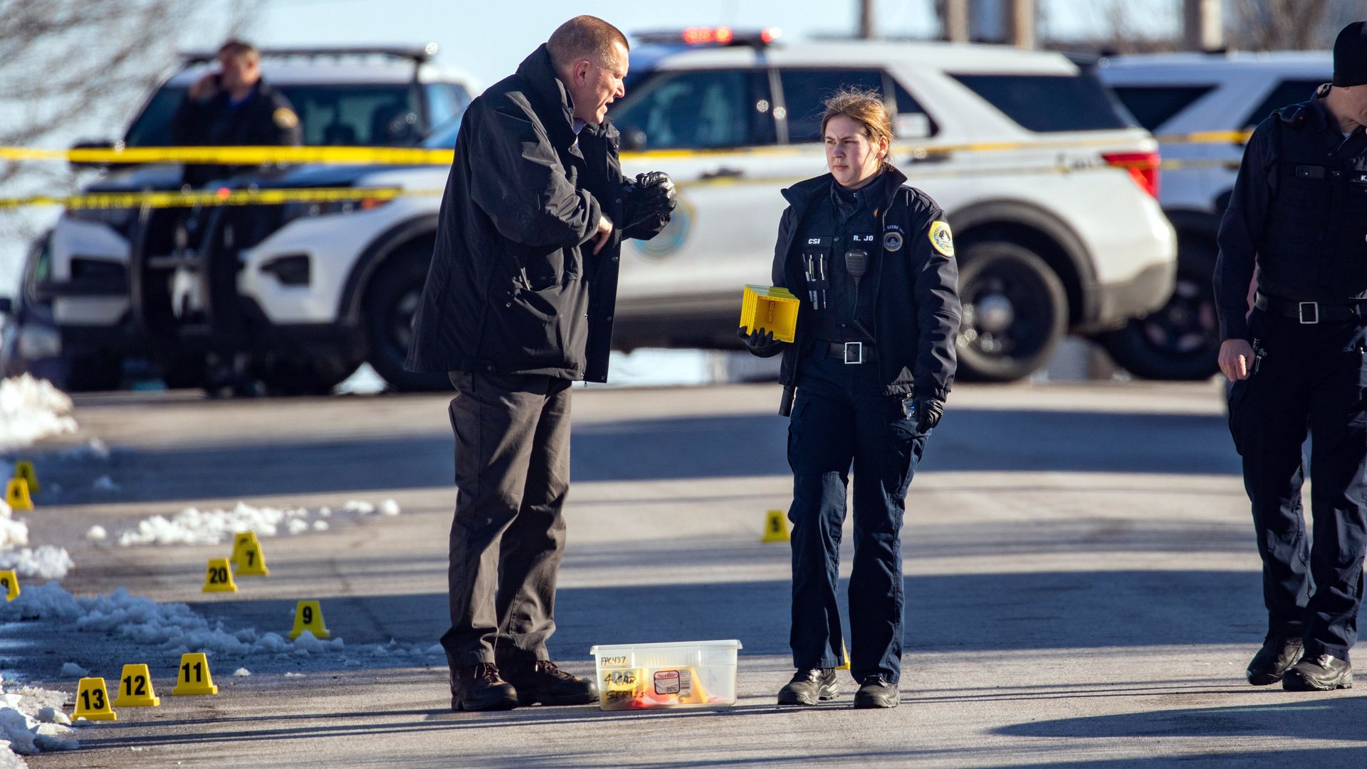 Two police officers set down crime scene markers outside of a Des Moines high school where a shooting took place on Monday.