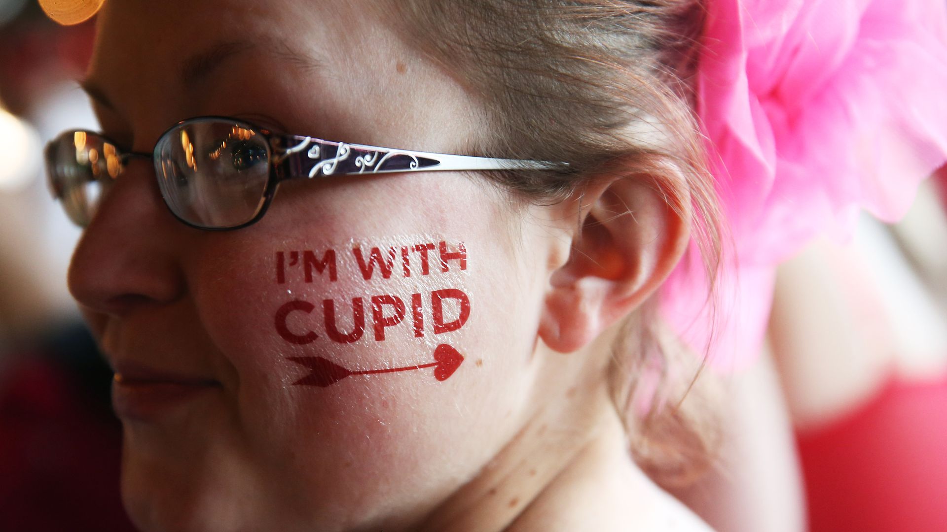 A woman with the words I'm With Cupid in a fake tattoo on her face.