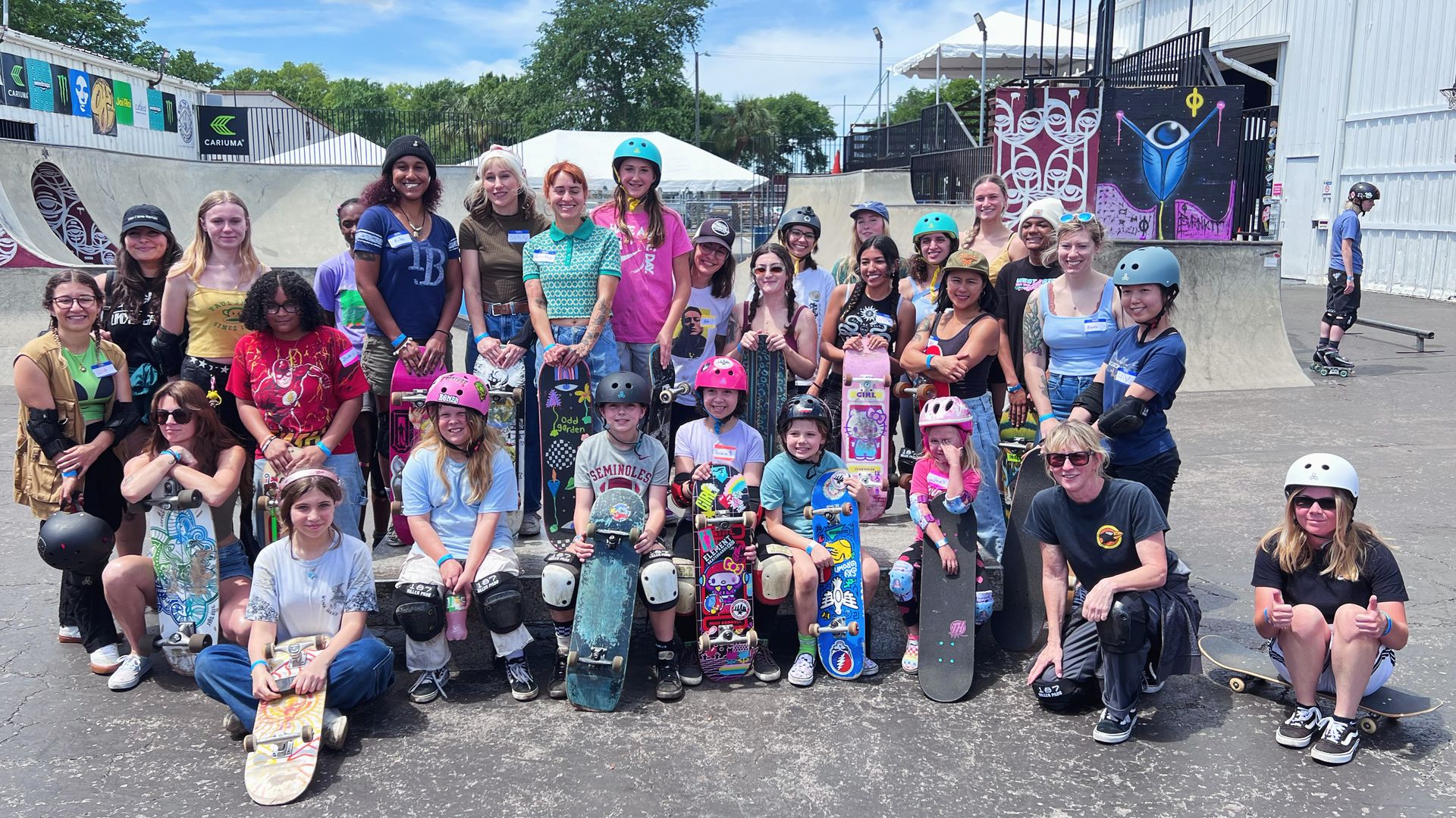 A group of about 40 women and girls holding skatebboards.