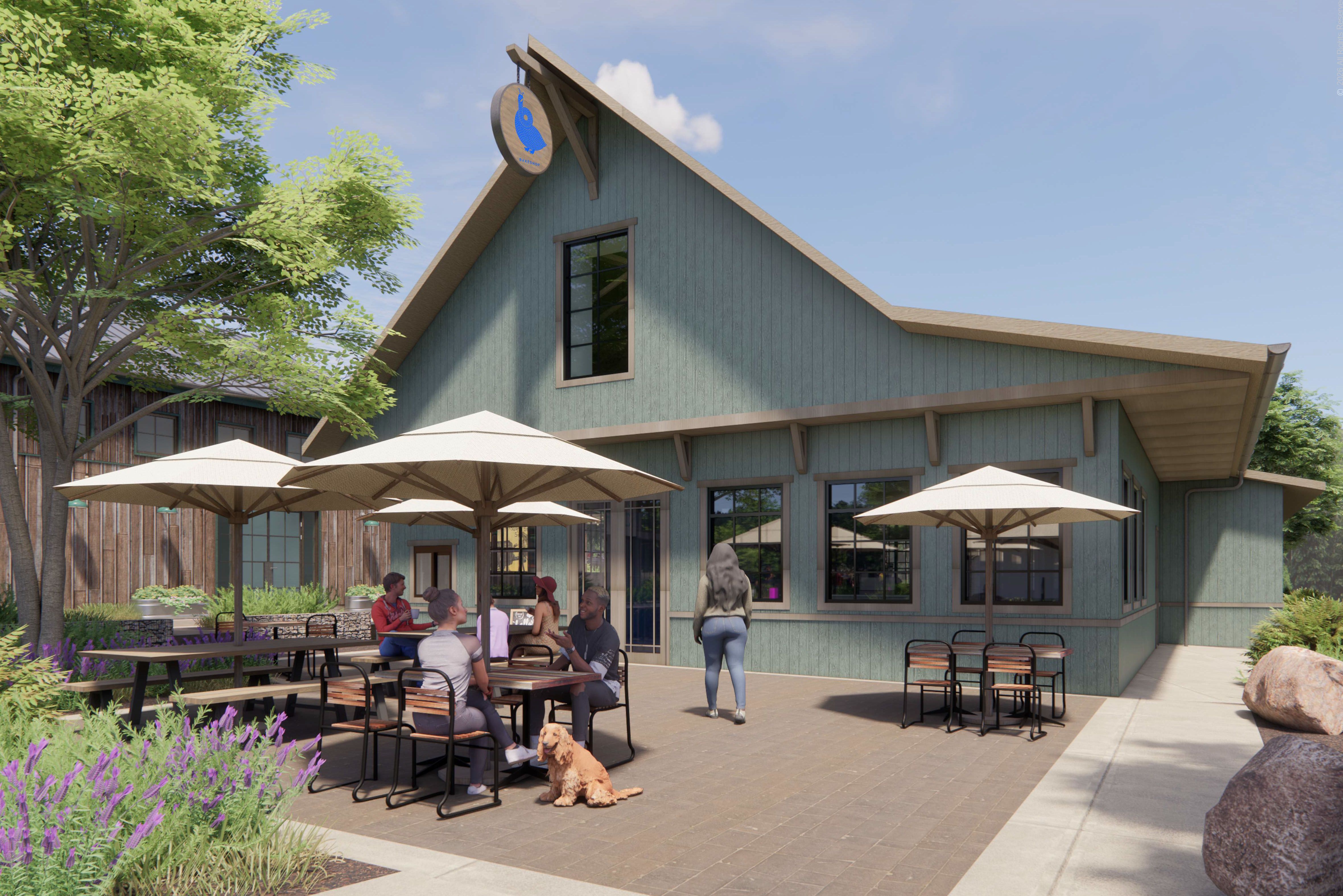 Blue-green cafe with a sloped roof and outdoor patio. People sit at tables under beige umbrellas; a person stands by the door, and a dog sits on the paving amid trees and lavender.