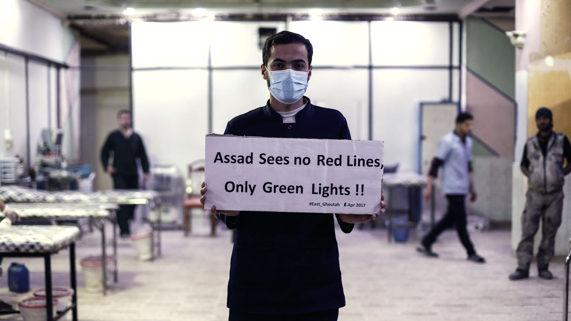 A medical worker at Damascus Countryside Specialised Hospital holds a placard condemning a suspected chemical weapons attack on the Syrian town in April 2017