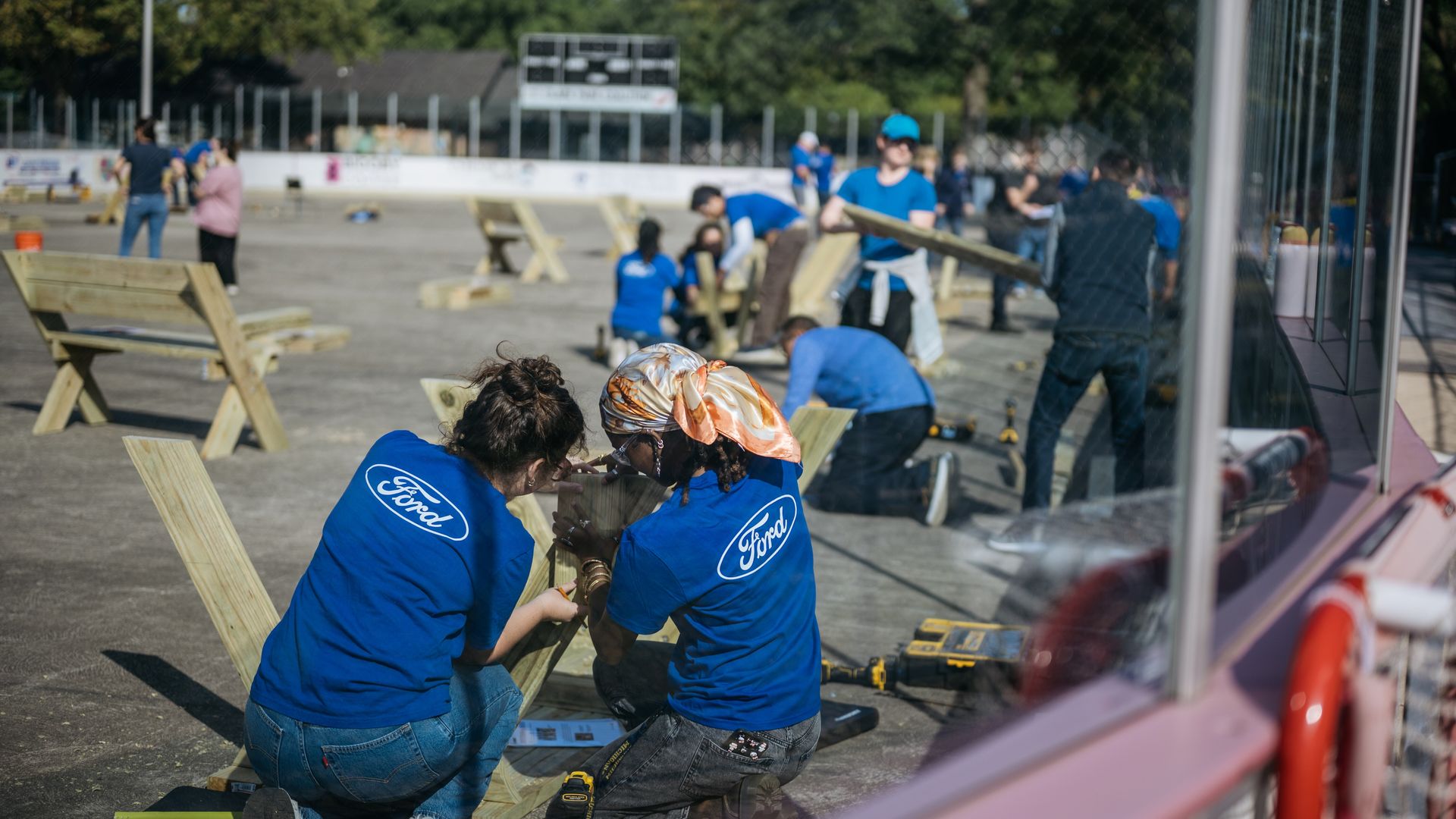 Volunteers wearing blue Ford shirts work on assembling wooden benches