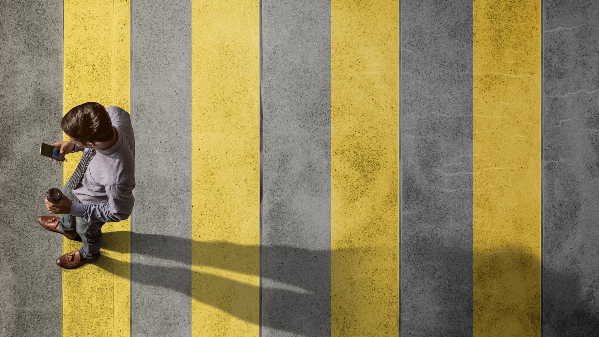 Man looking at cell phone crosses street