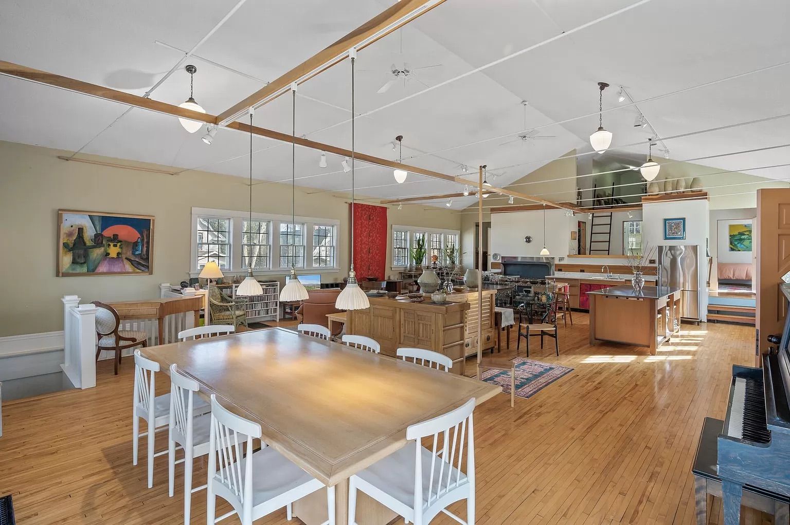 A large room with a kitchen table, couch, cabinets and television.