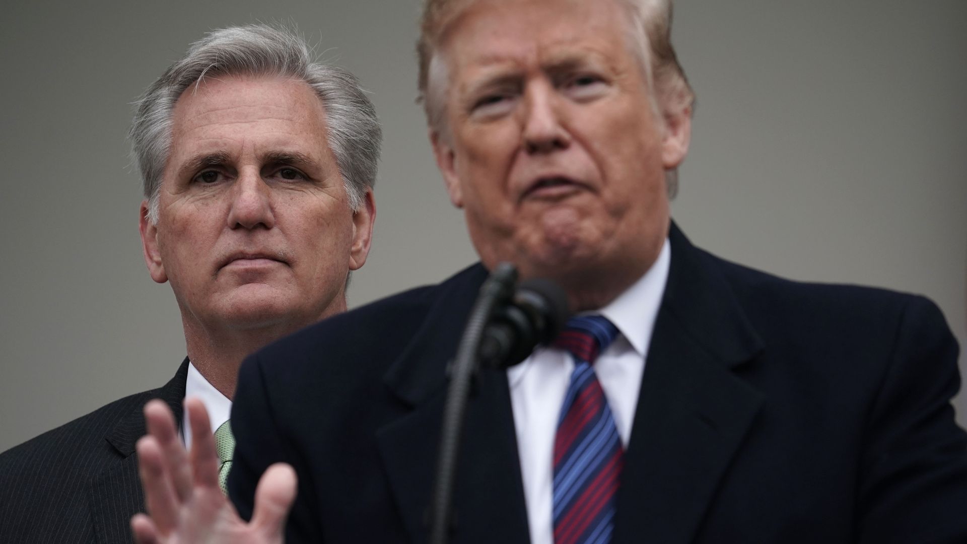 Picture of Donald Trump speaking into a microphone with Kevin McCarthy standing in the background