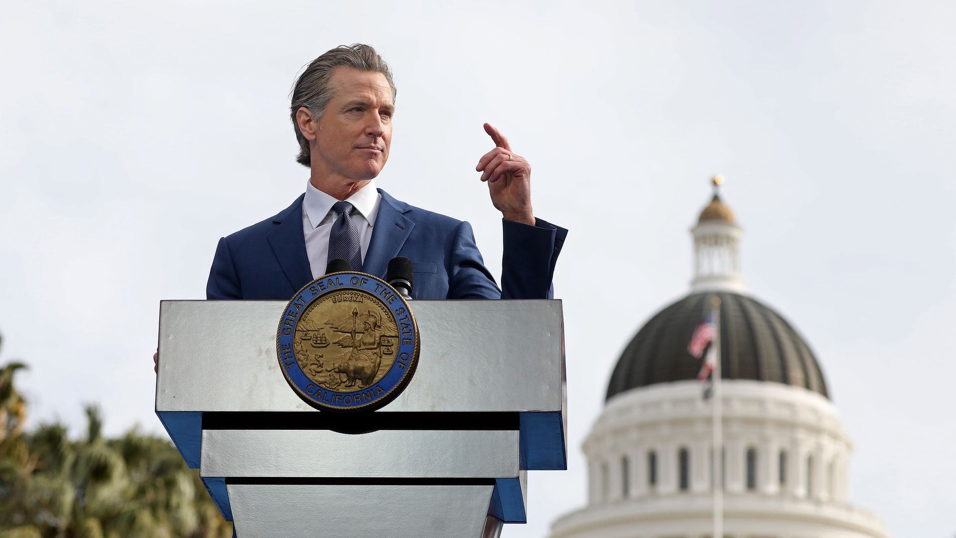 Photo of Gavin Newsom speaking from a podium in front of the California state capitol