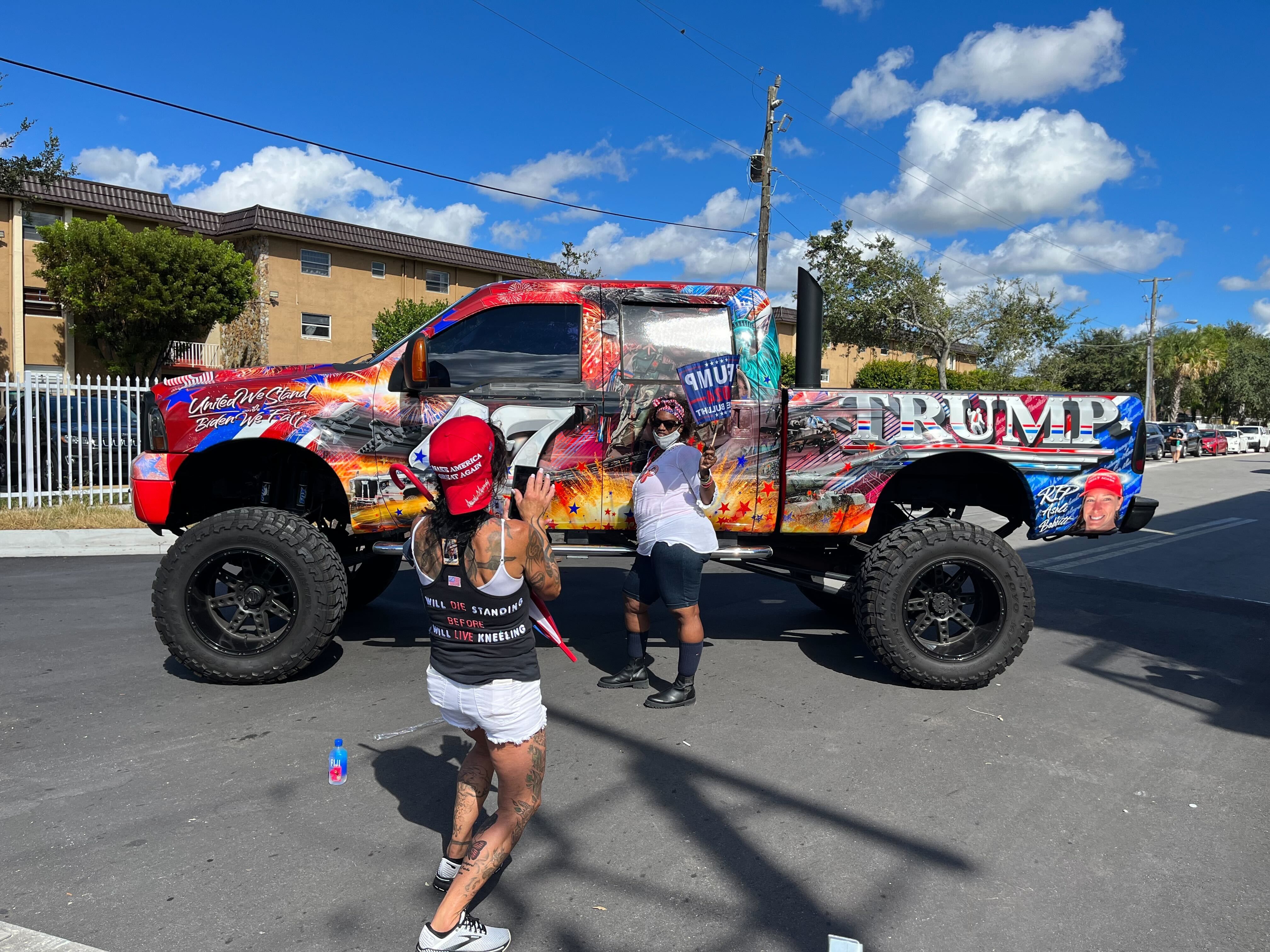 Trump supporters pose in front of a MAGA-themed pickup truck.