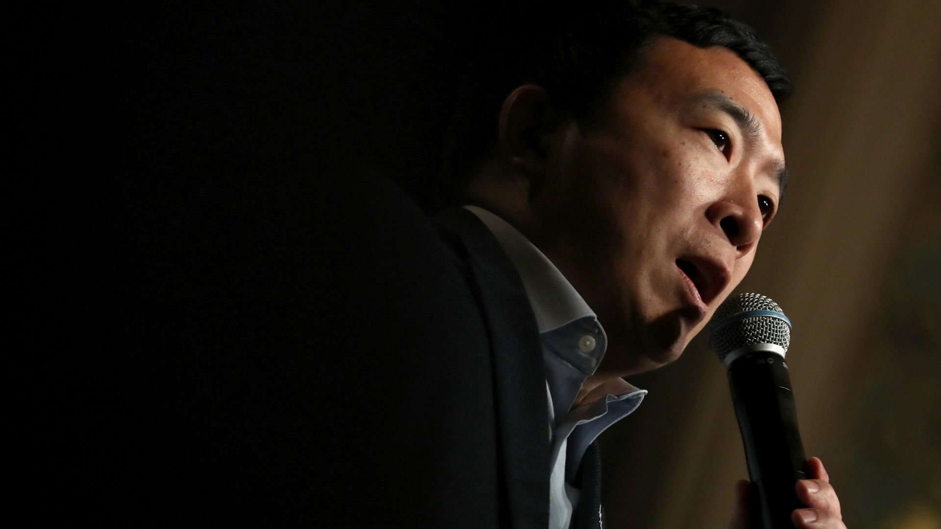 This image shows Andrew Yang holding a microphone.