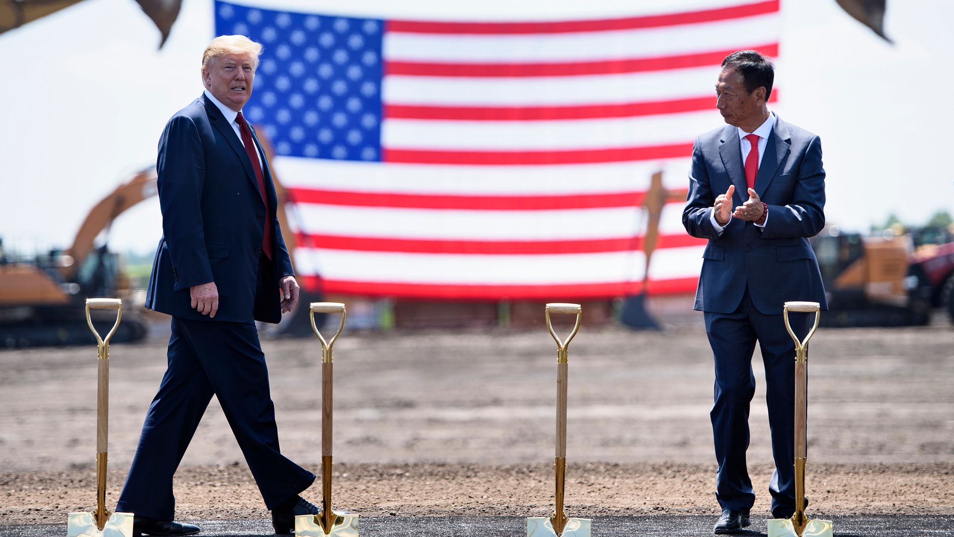 Donald Trump walks to Foxconn Chairman Terry Gou at groundbreaking with shovels and American flag.