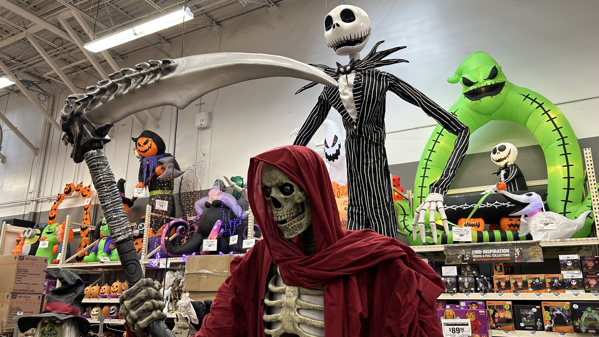 A photo of a Halloween decoration floor display at Home Depot. That includes a skeleton Grim Reaper and a tall character from A Nightmare before Christmas.