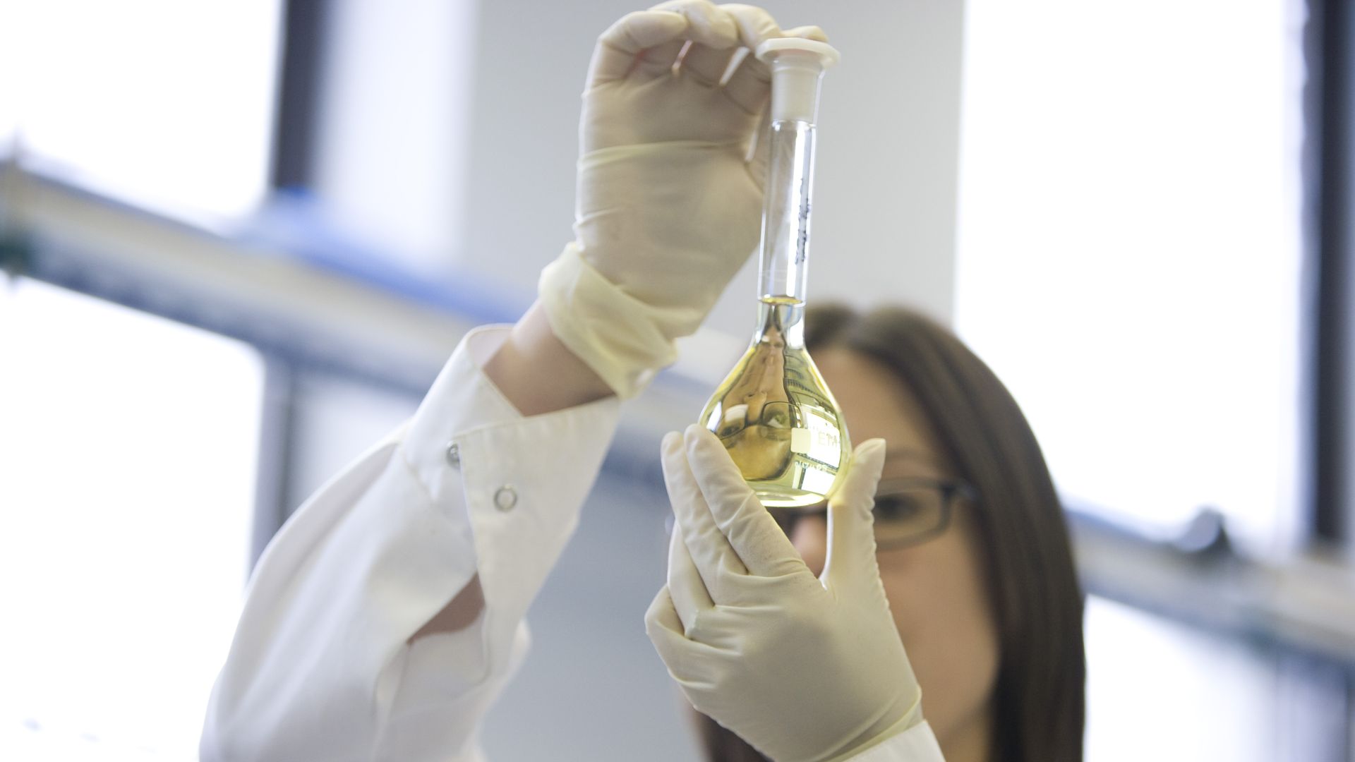 Photo of lab technician holding up flask of liquid