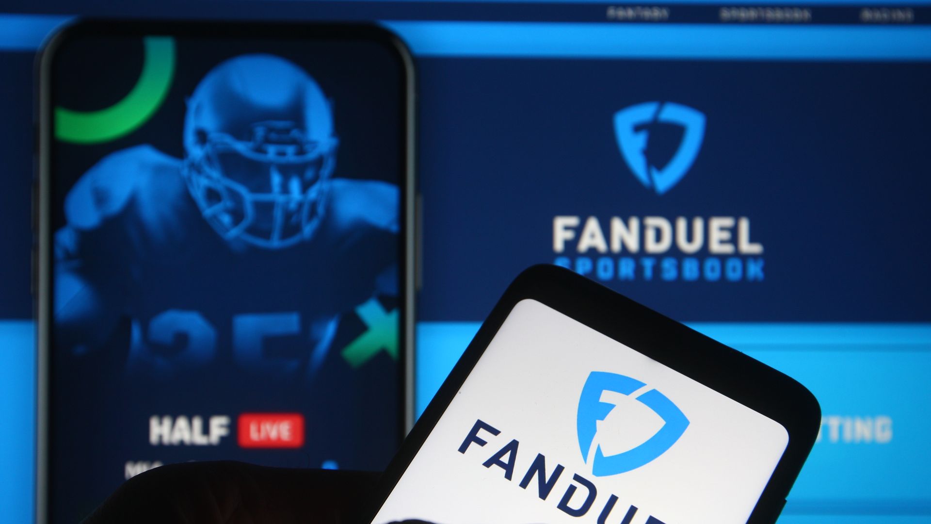 Close-up of two smartphones displaying FanDuel logos and a digital interface with a blue football player image and text related to sports betting and fantasy sports.
