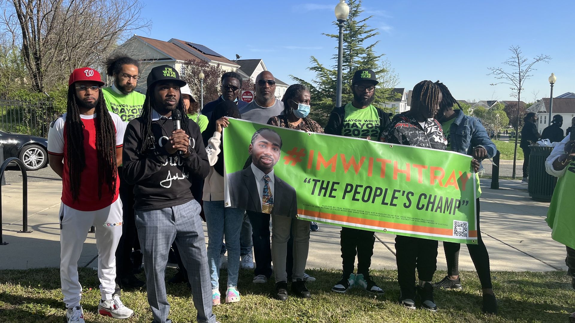 Trayon White stands with a microphone in front of his supporters holding a banner for his mayoral campaign at a press conference