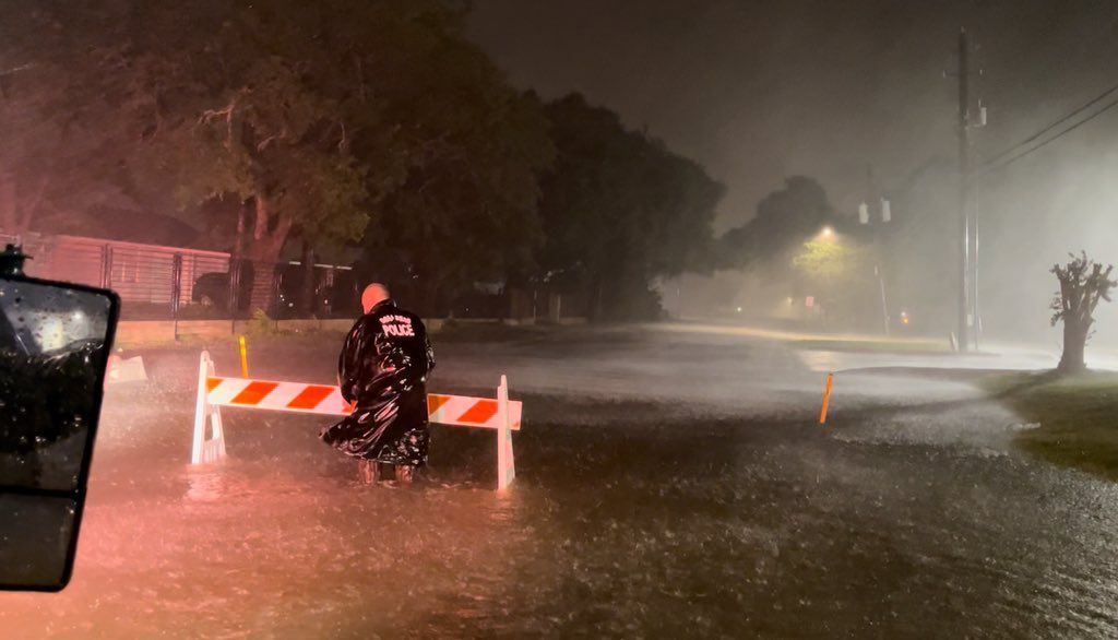 A Rosenberg police officer walks in a flooded roadway