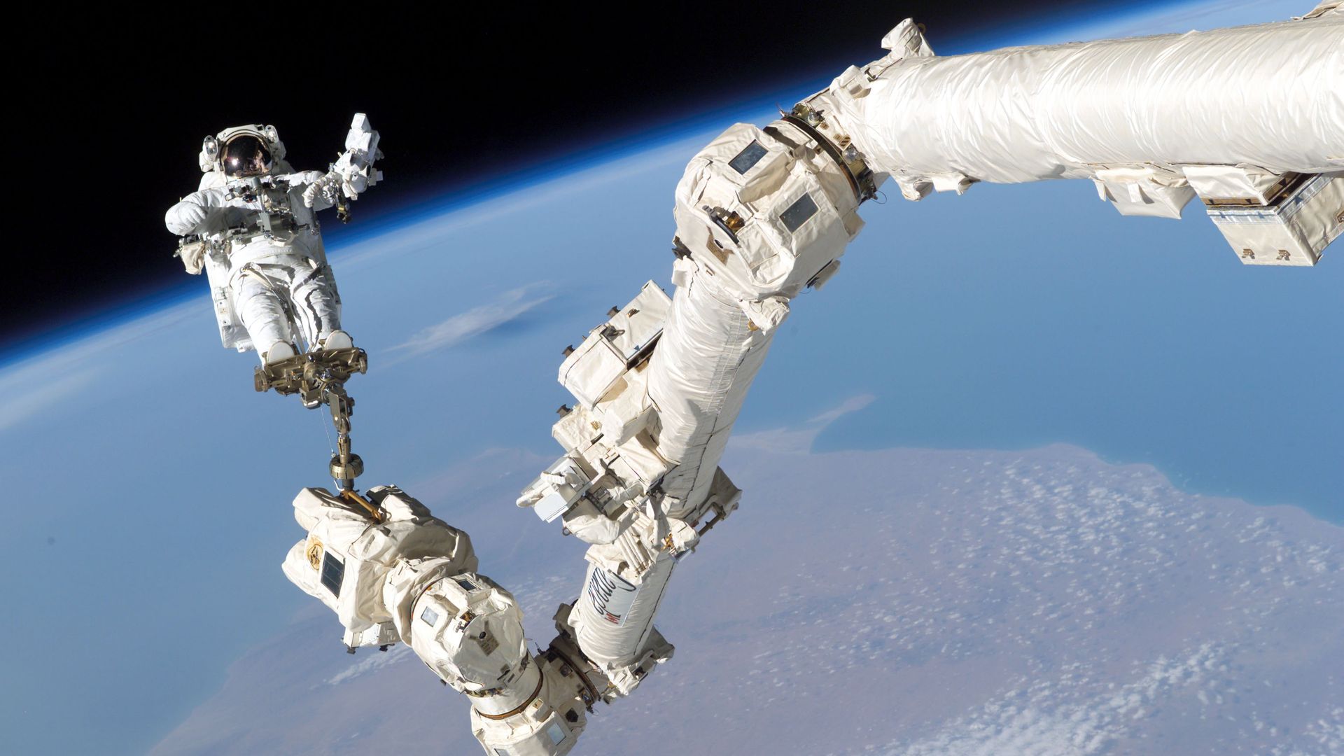 NASA astronaut Stephen K. Robinson anchored to the International Space Station's robotic arm during a spacewalk in August 2005.
