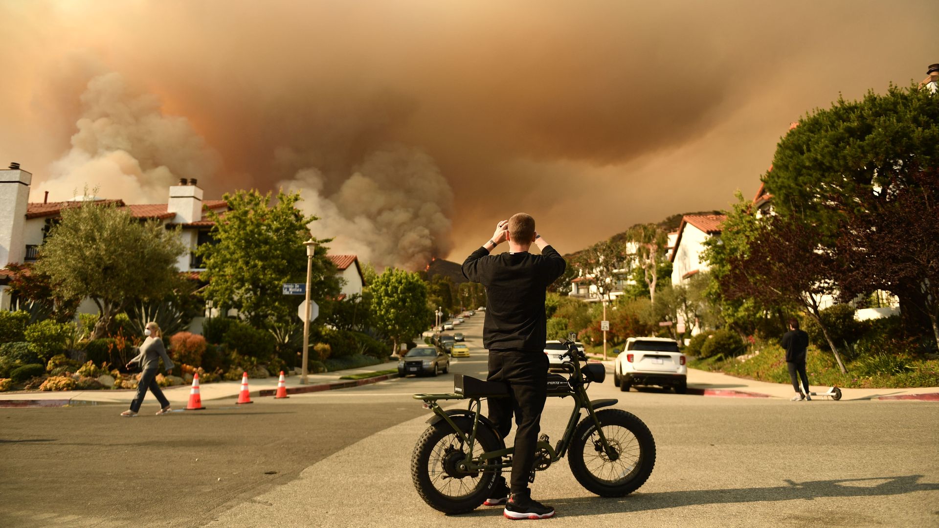 A man takes a photo of the plume of smoke created by the Palisades fire in Topanga State Park, North West of Los Angeles on May 15, 2021.