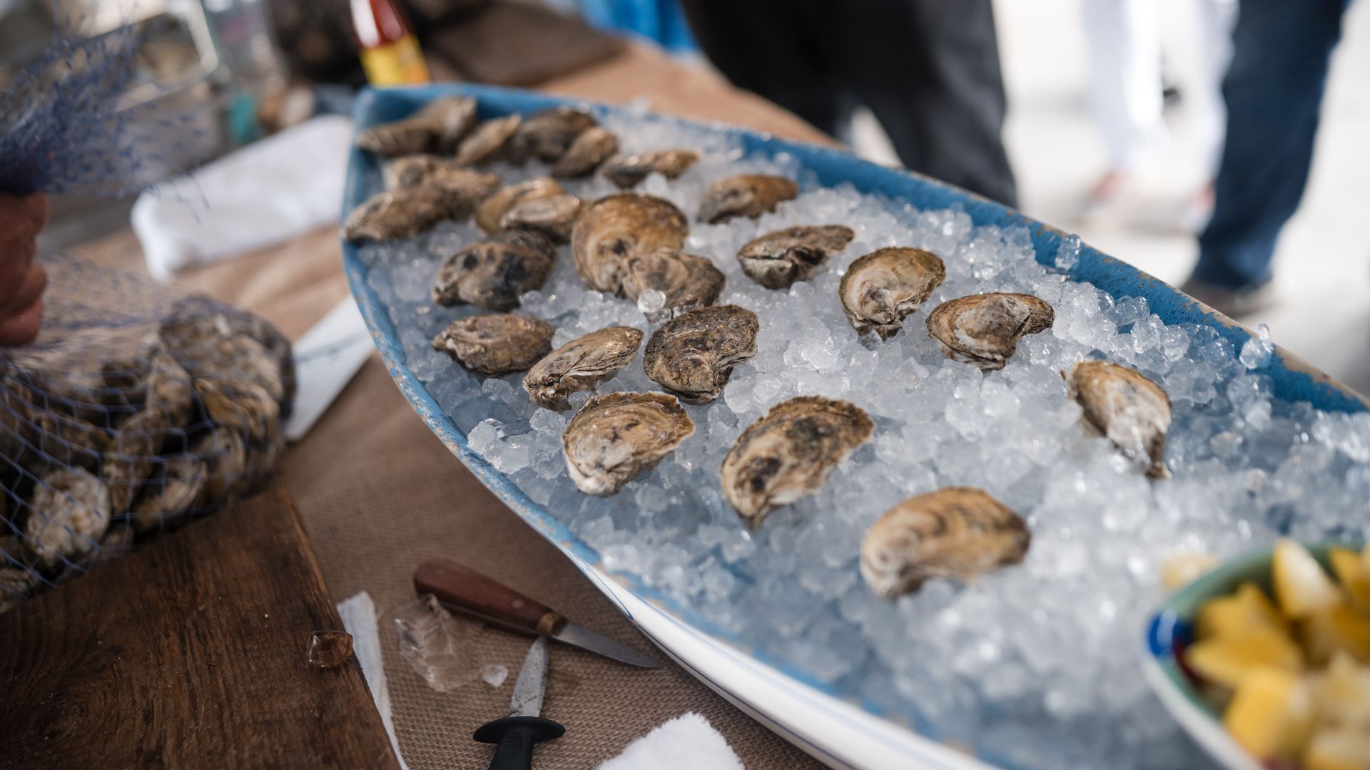 A boat-shaped serving vessel is filled with ice and shucked oysters.
