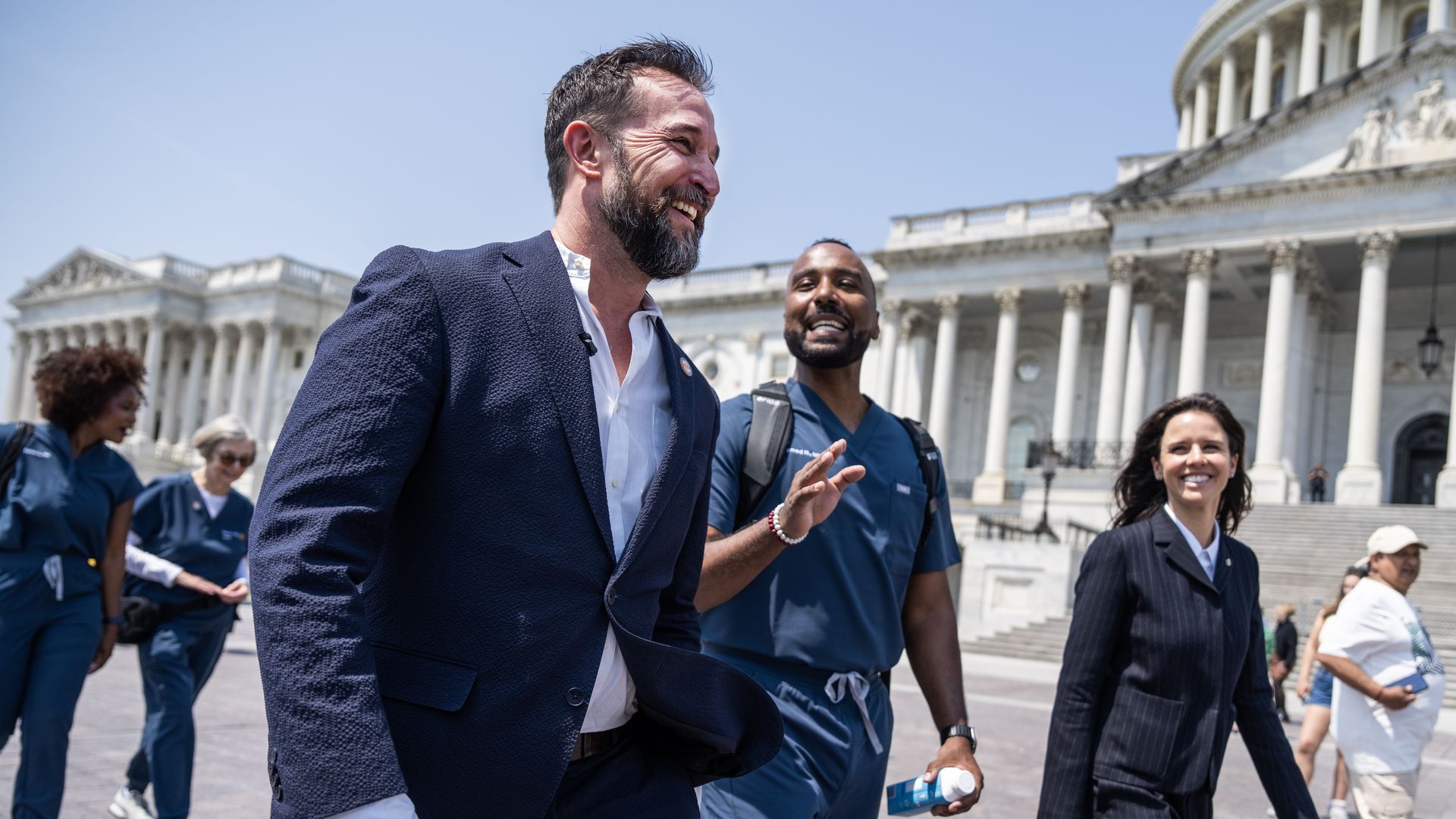 Noah Wyle walks alongside healthcare professionals in medical scrubs outside of the U.S. Capitol.