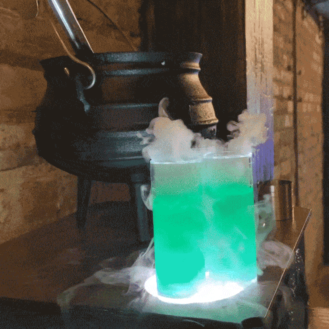 Two green cocktails by a cauldron.