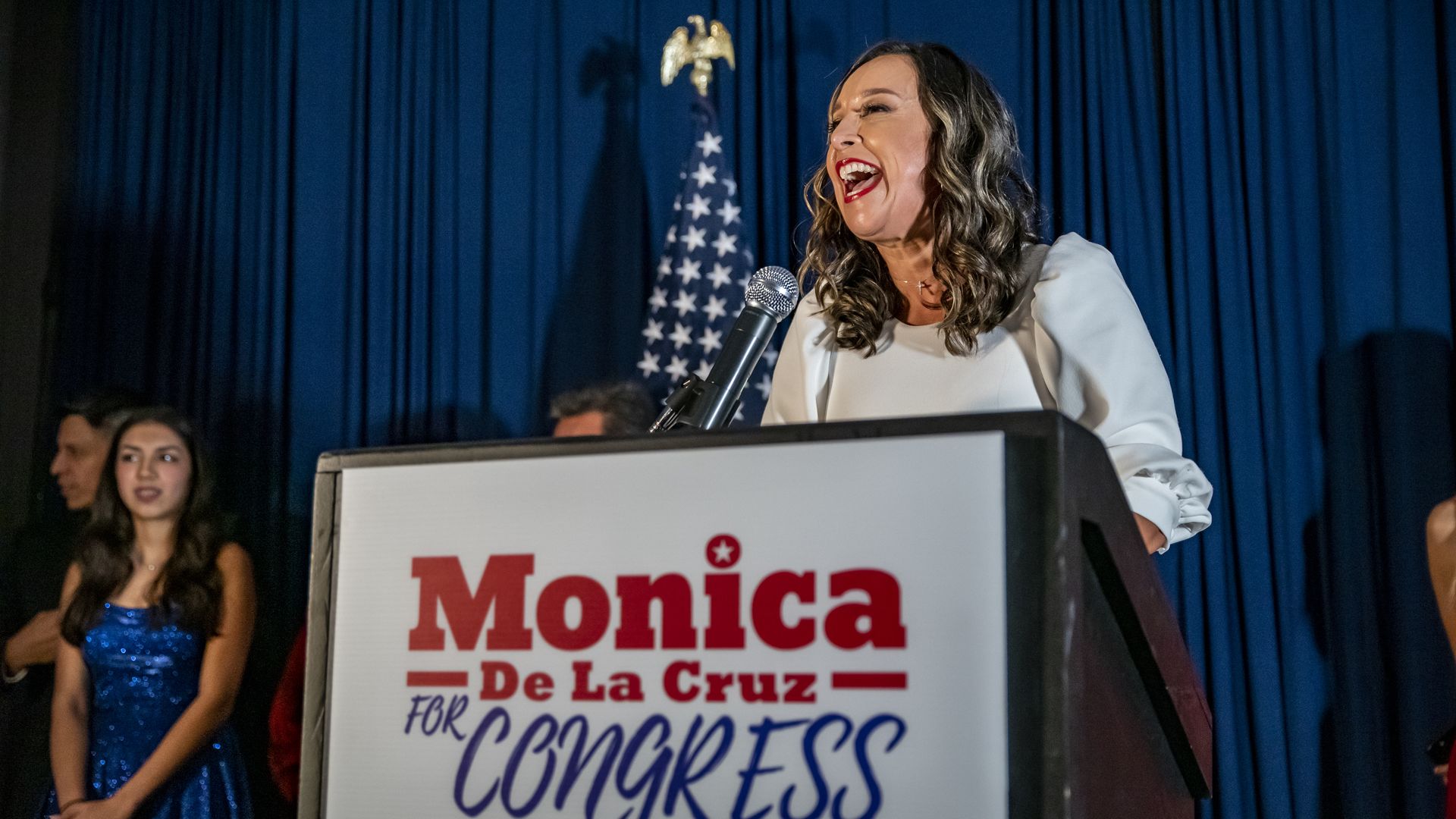 De La Cruz speaking at a podium at her watch party on election night in 2020. The podium has her campaign sign on it. 