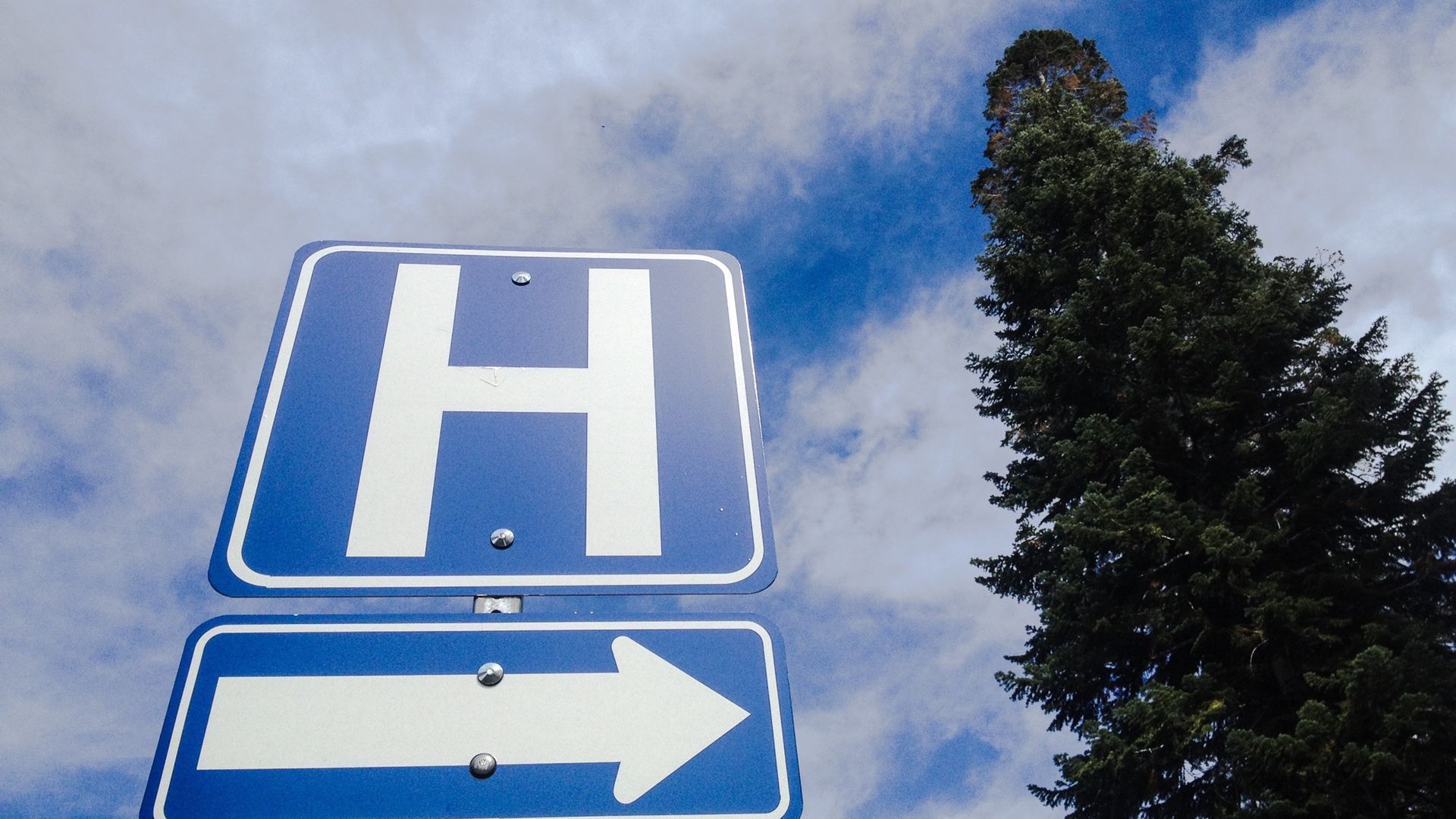 A hospital sign with the sky in the background.