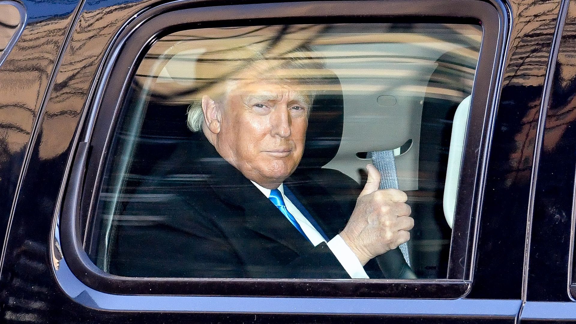 Donald Trump is pictured giving a thumbs up through a car window 