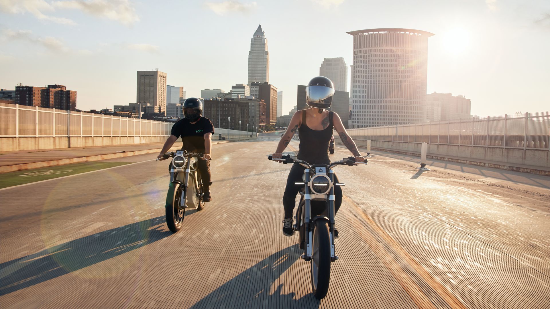 Photo of two riders on emotorcycles with Cleveland skyline in the background