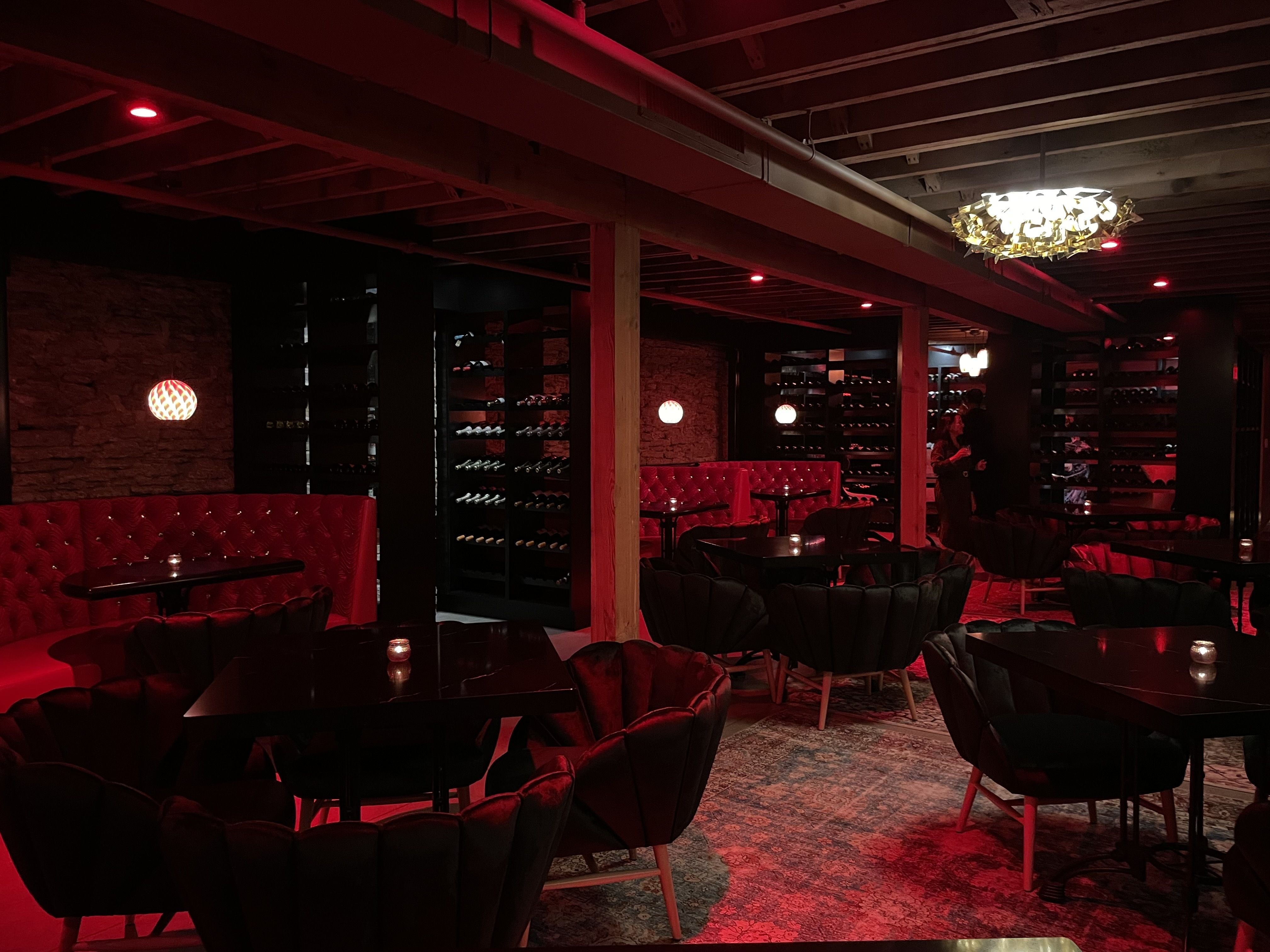 A room with red booths and black chairs, lit with red lighting.