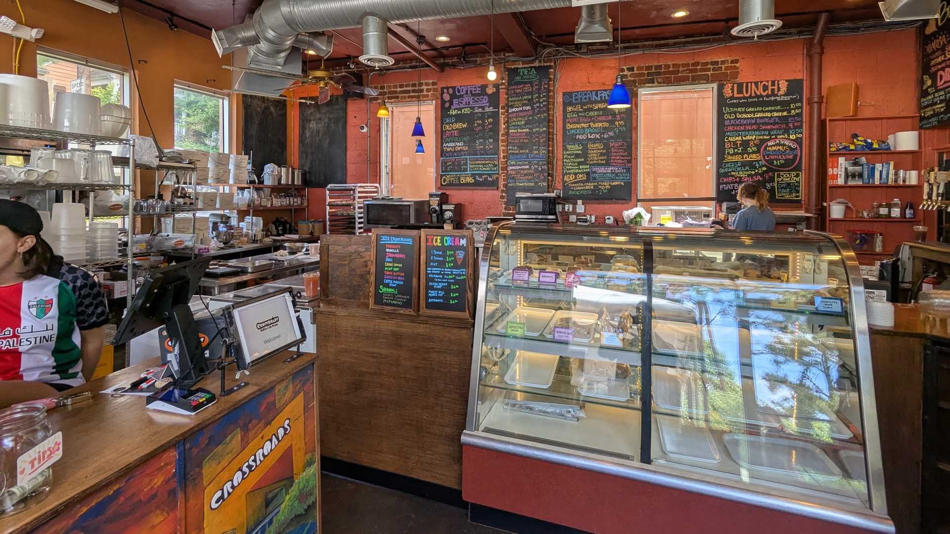 The inside of a coffeeshop with menu boards and a dessert case 