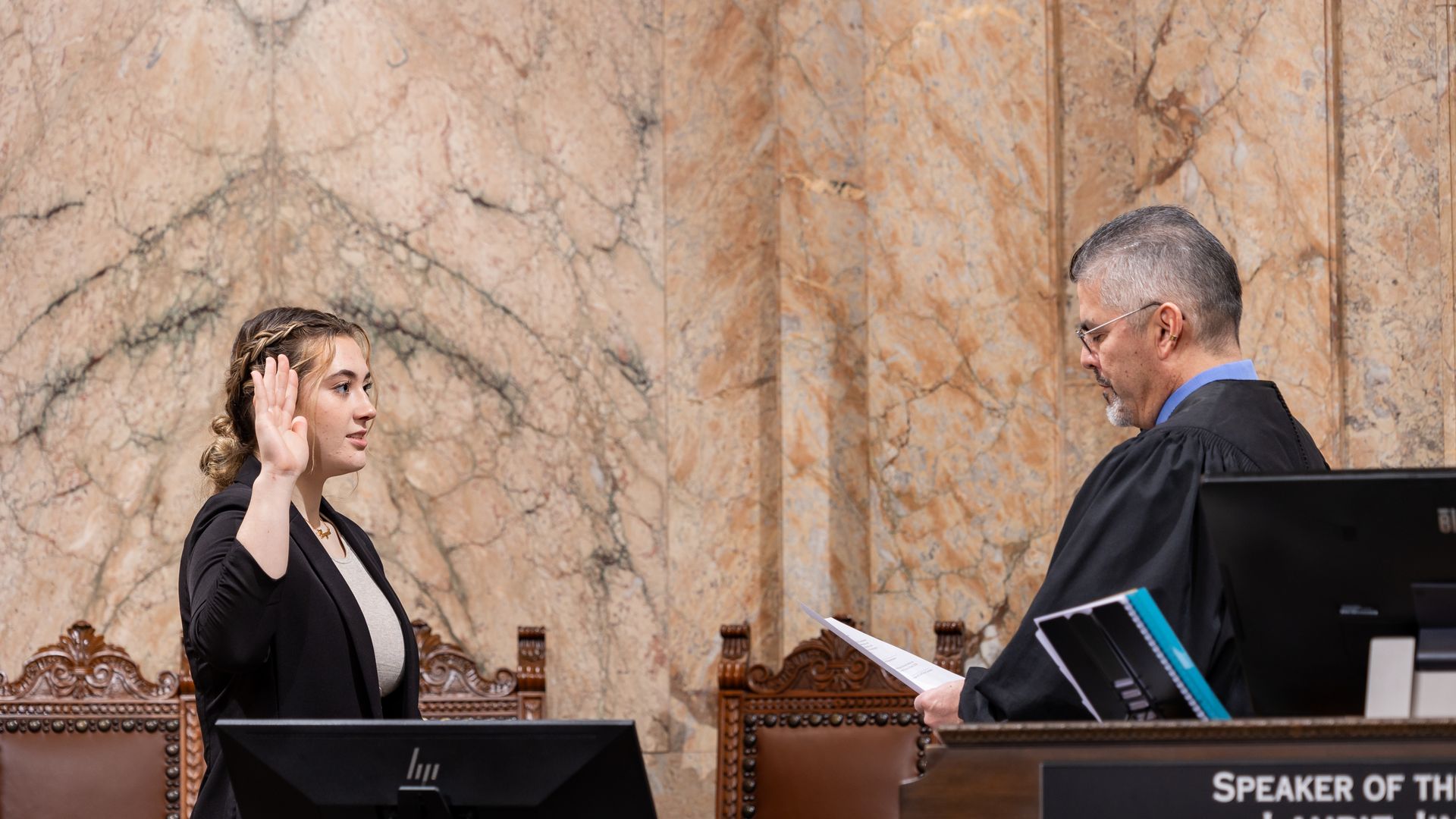 A young state legislator holds up her hand as she is sworn into office. 
