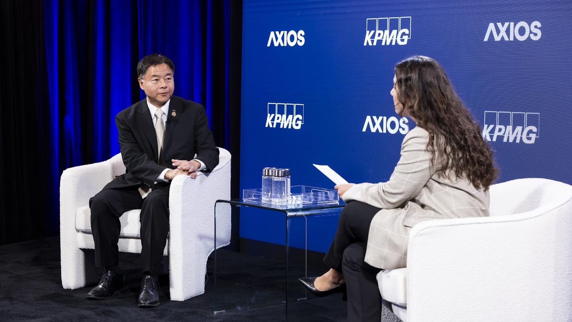 Two people sitting in white chairs talking
