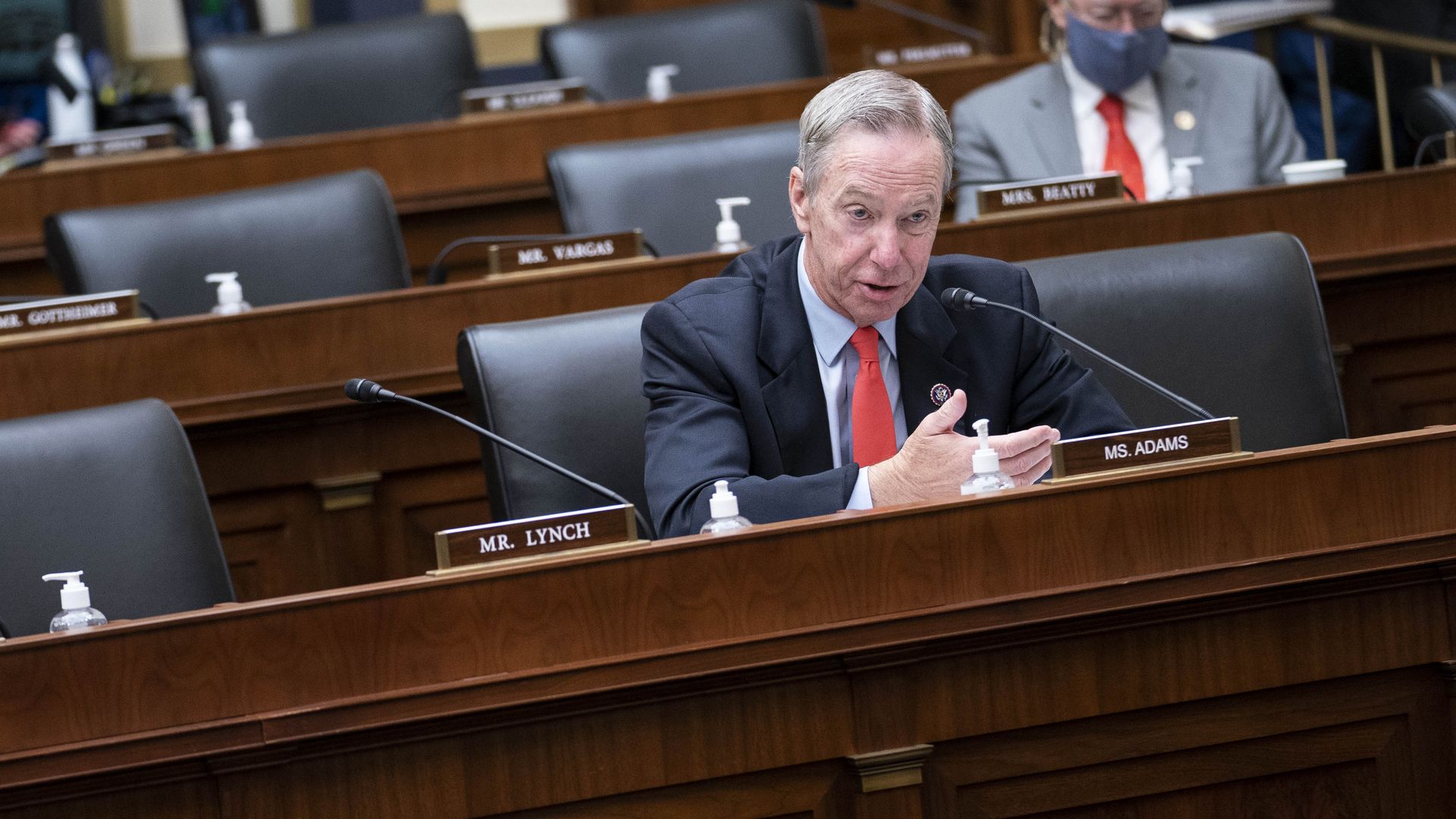 Rep. Stephen Lynch, wearing a blue suit, light blue shirt and red tie, speaks into a microphone at a congressional hearing.